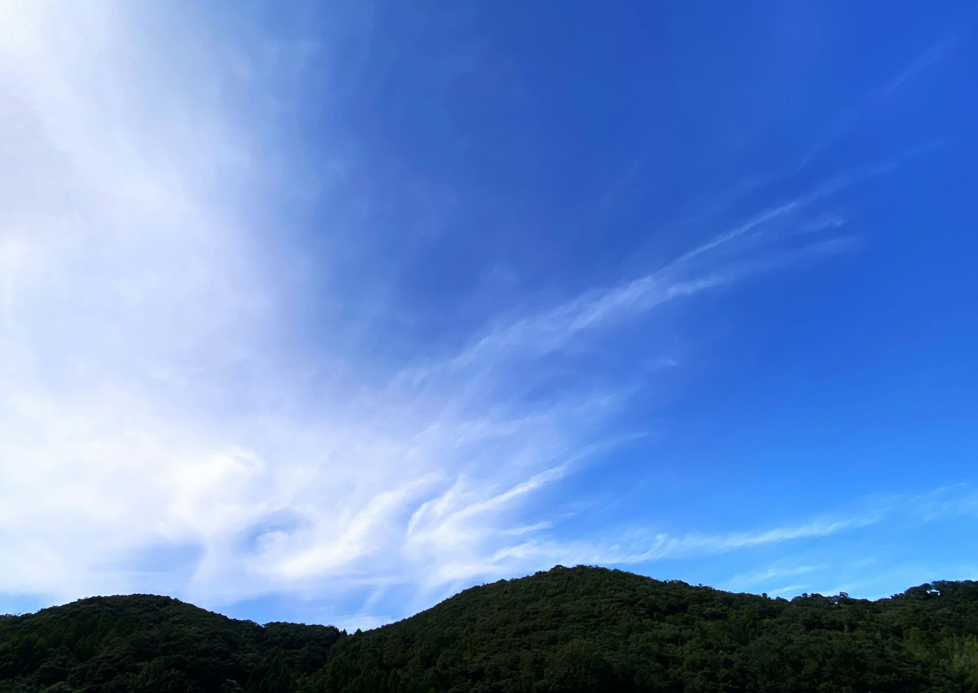 Vista del cielo azul con nubes blancas sobre colinas verdes