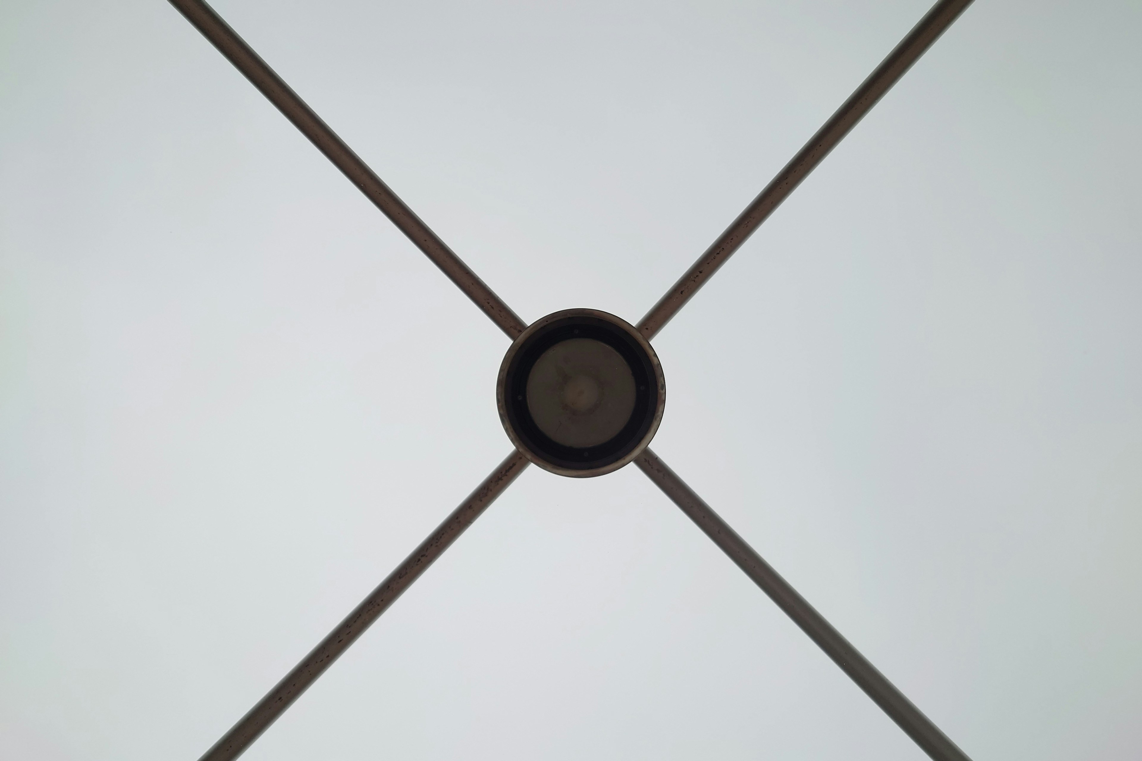 Ceiling view featuring a central black circle and intersecting metal rods