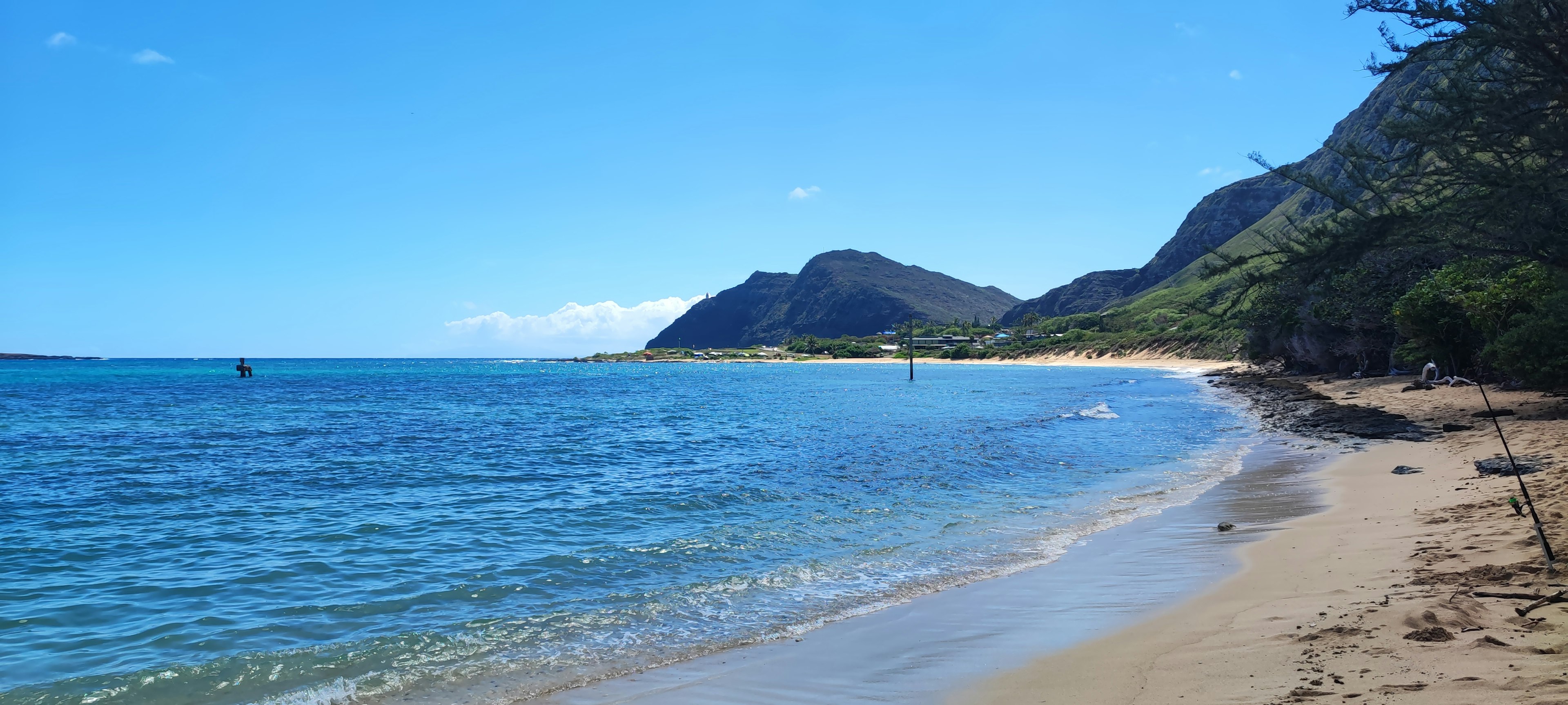 Panoramablick auf einen blauen Ozean und einen Sandstrand mit Bergen im Hintergrund