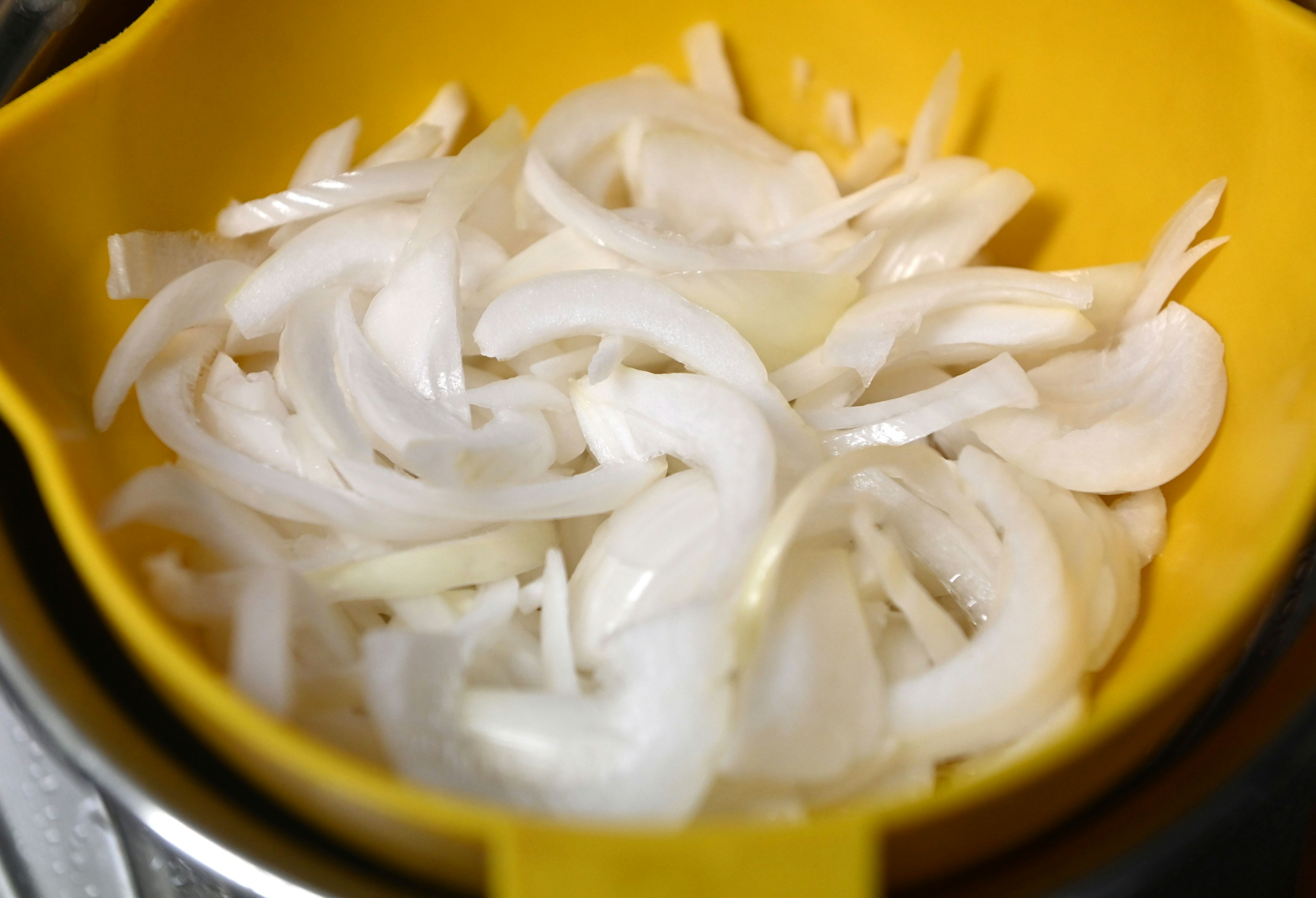 In Scheiben geschnittene Zwiebeln in einer gelben Schüssel