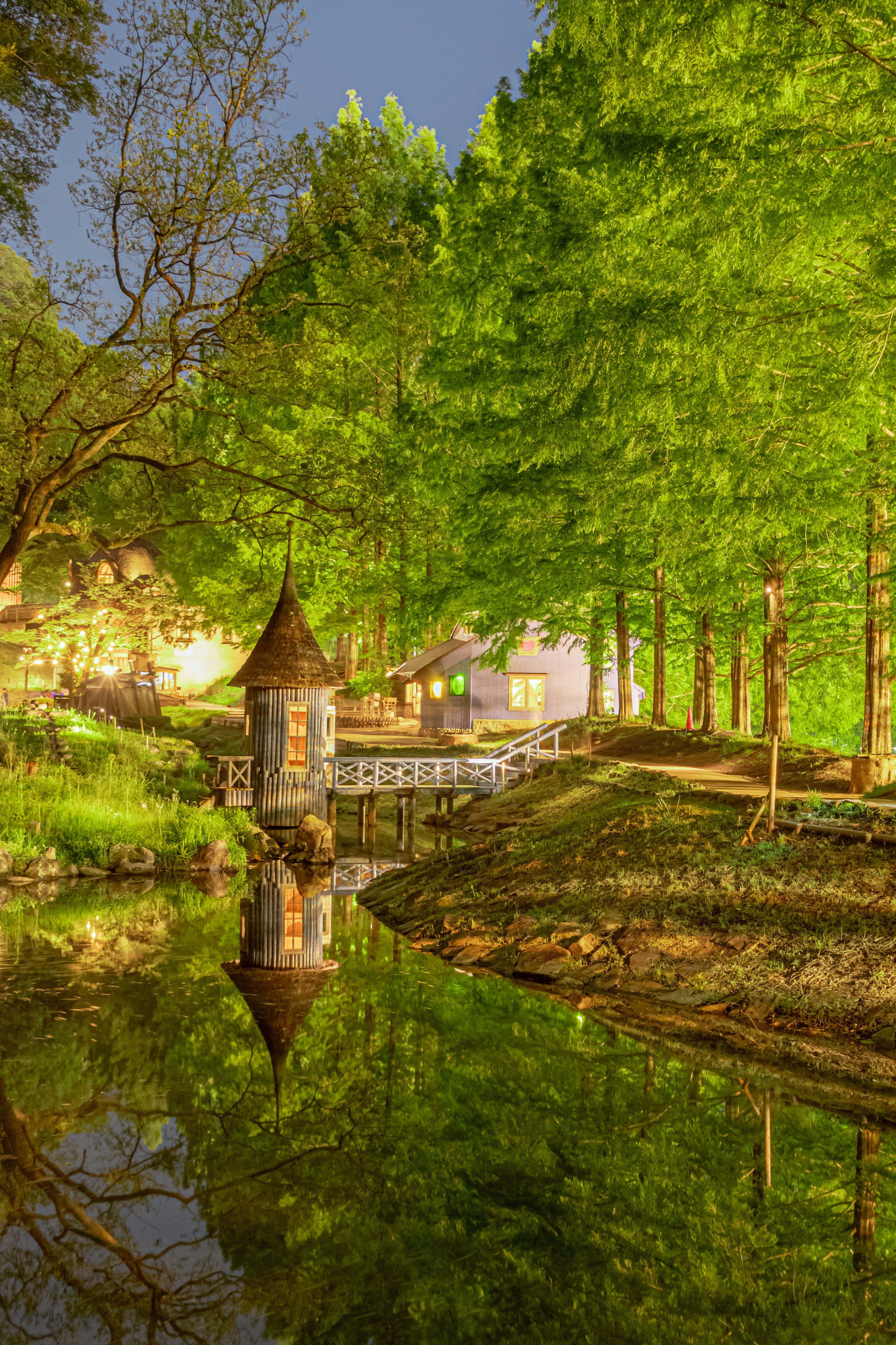 Malersicher Blick auf ein kleines Haus an einem Teich umgeben von üppigen grünen Bäumen