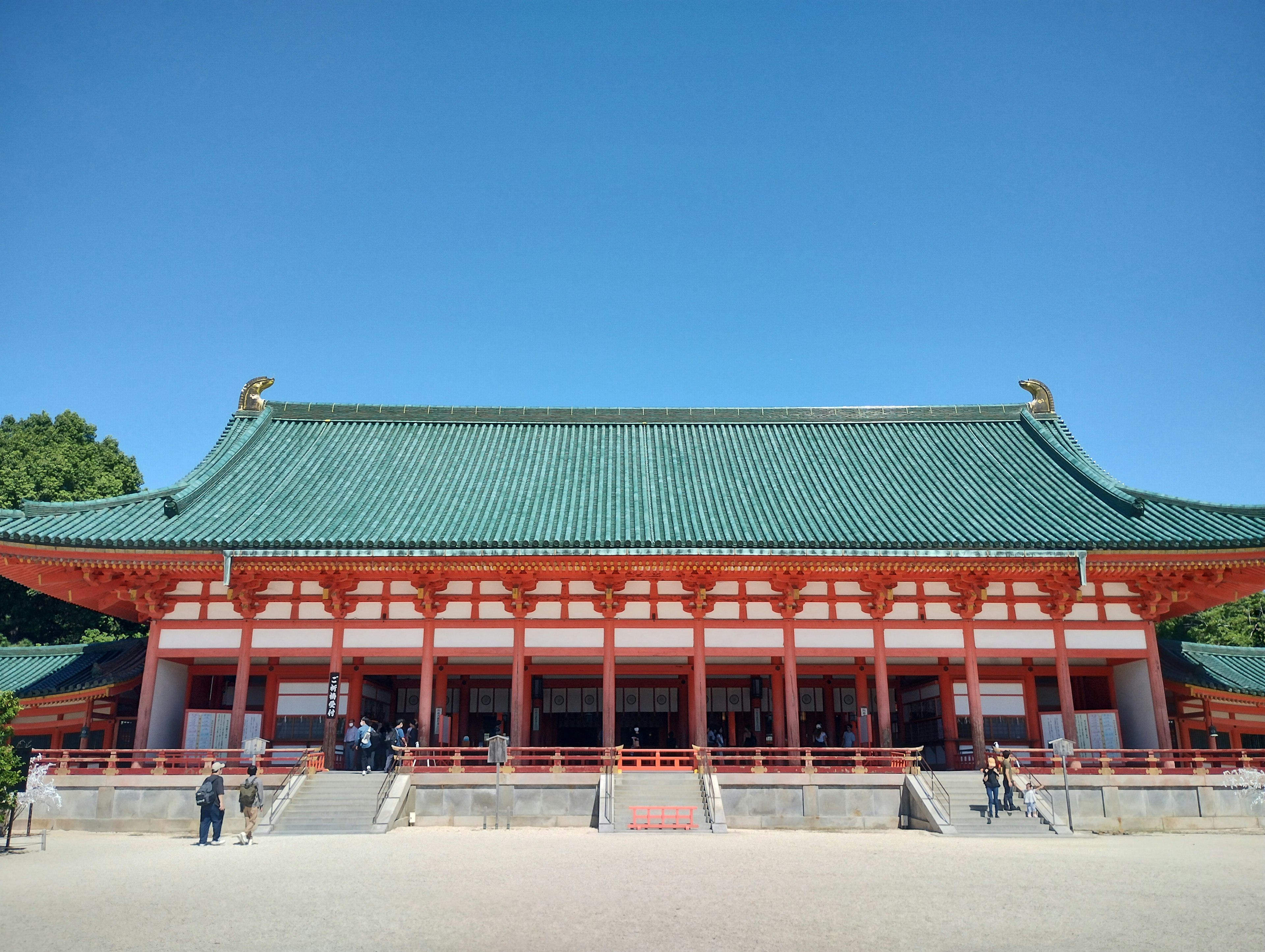 美しい緑色の屋根と赤い柱の伝統的な日本の建物が広々とした空間に立っている