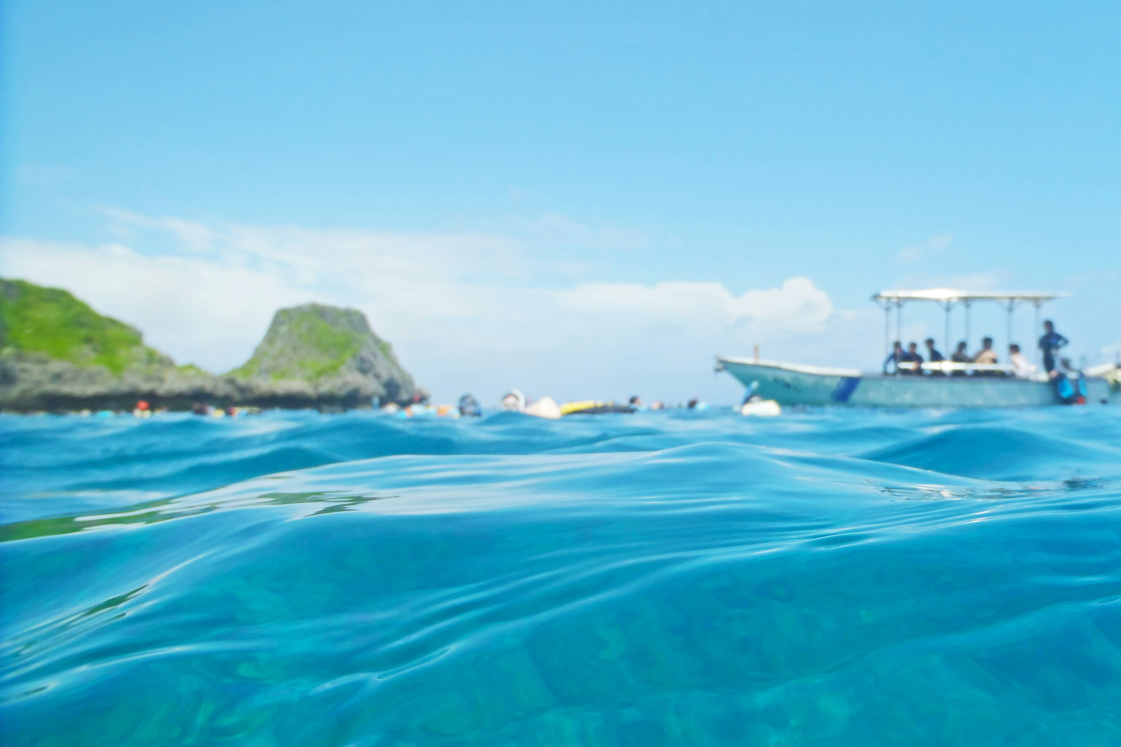 Pemandangan laut biru dengan gelombang lembut dan perahu di latar belakang