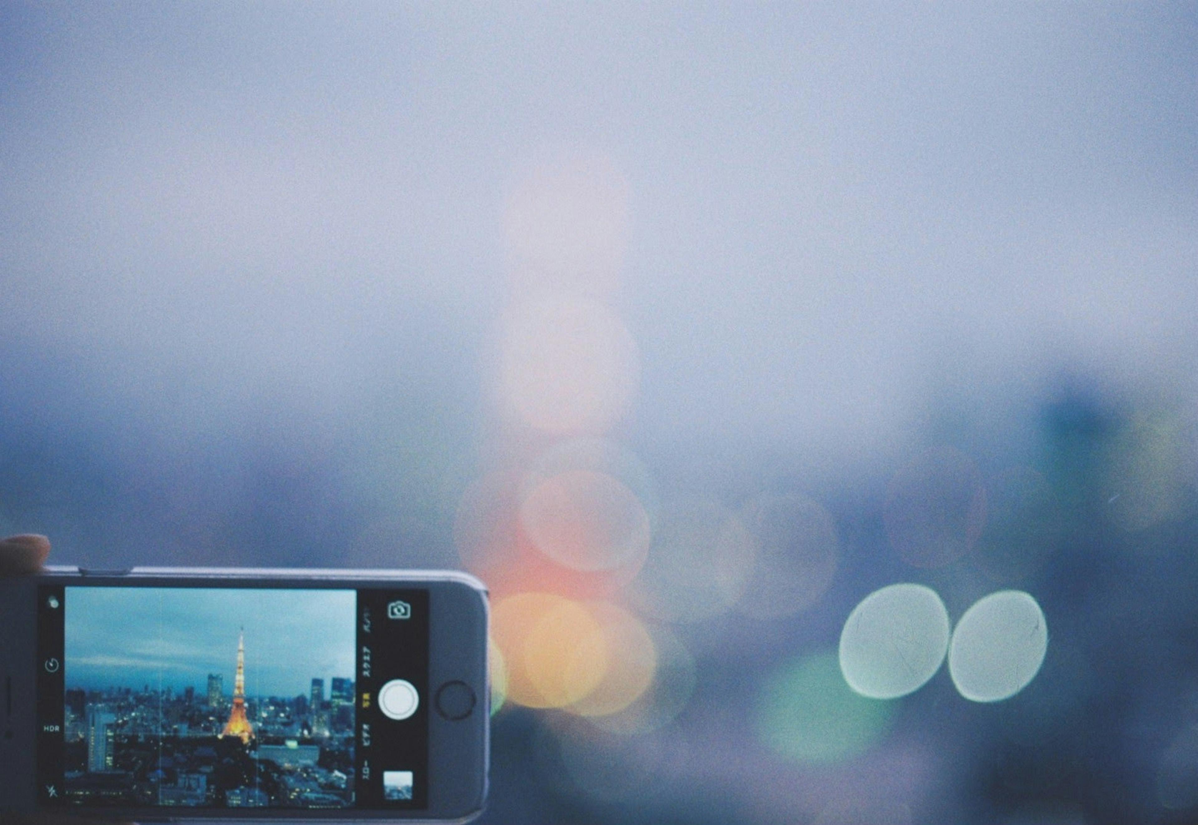 A smartphone capturing the Tokyo Tower with a blurred cityscape in the background