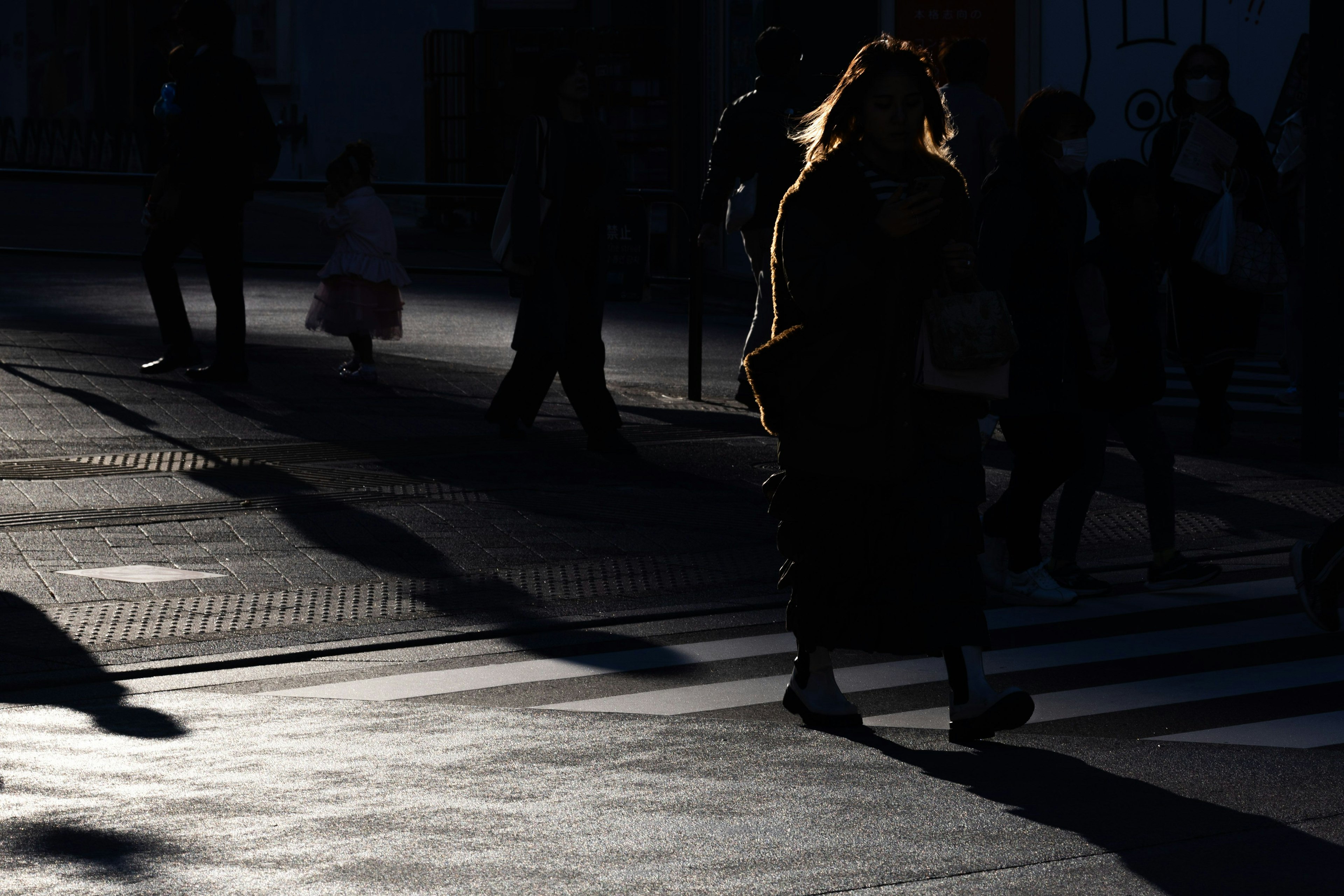 Siluetas de personas caminando en sombras en un paso de peatones