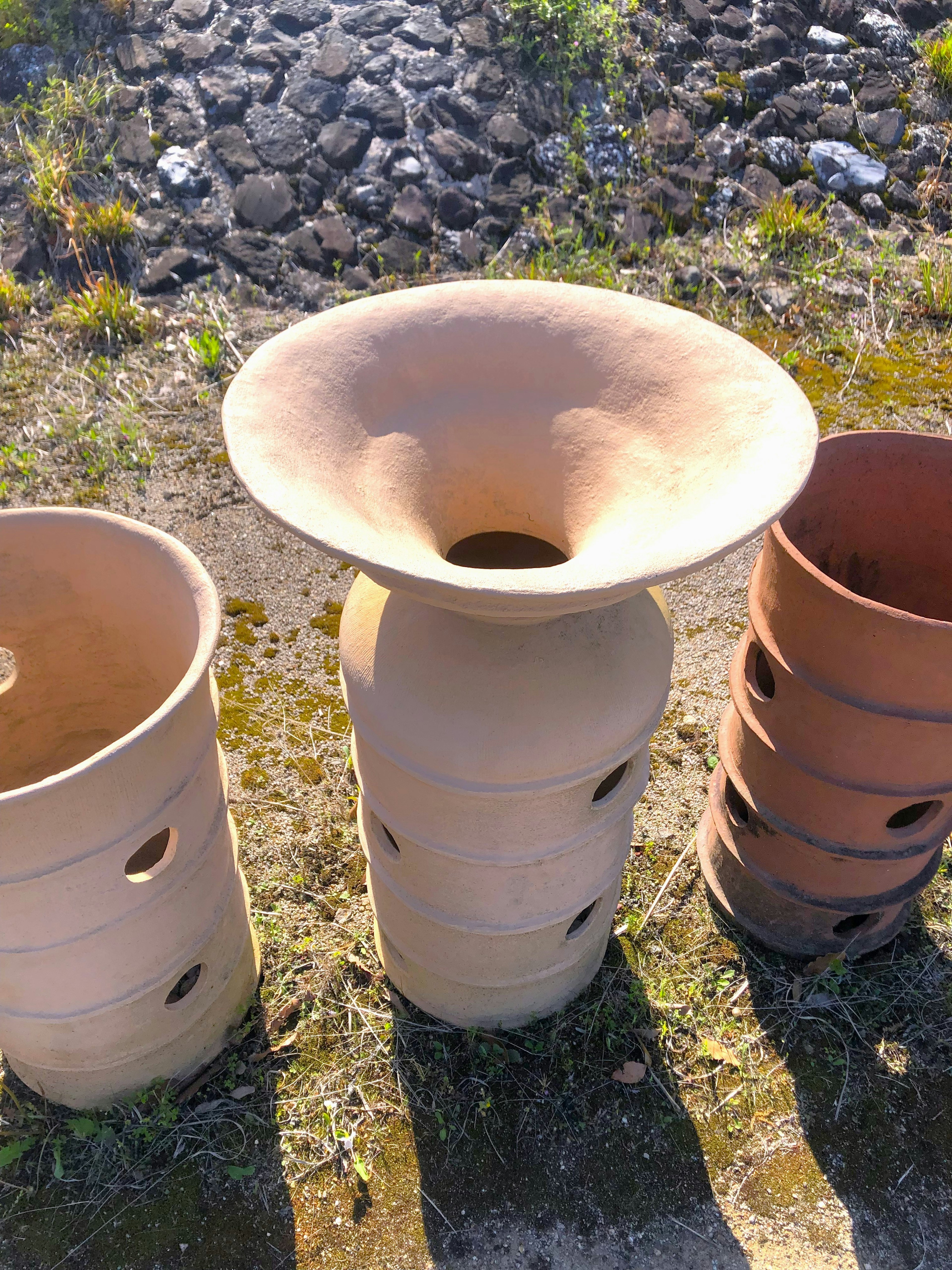 Una collezione di vasi in terracotta con un vaso centrale a bocca larga e fori sul corpo