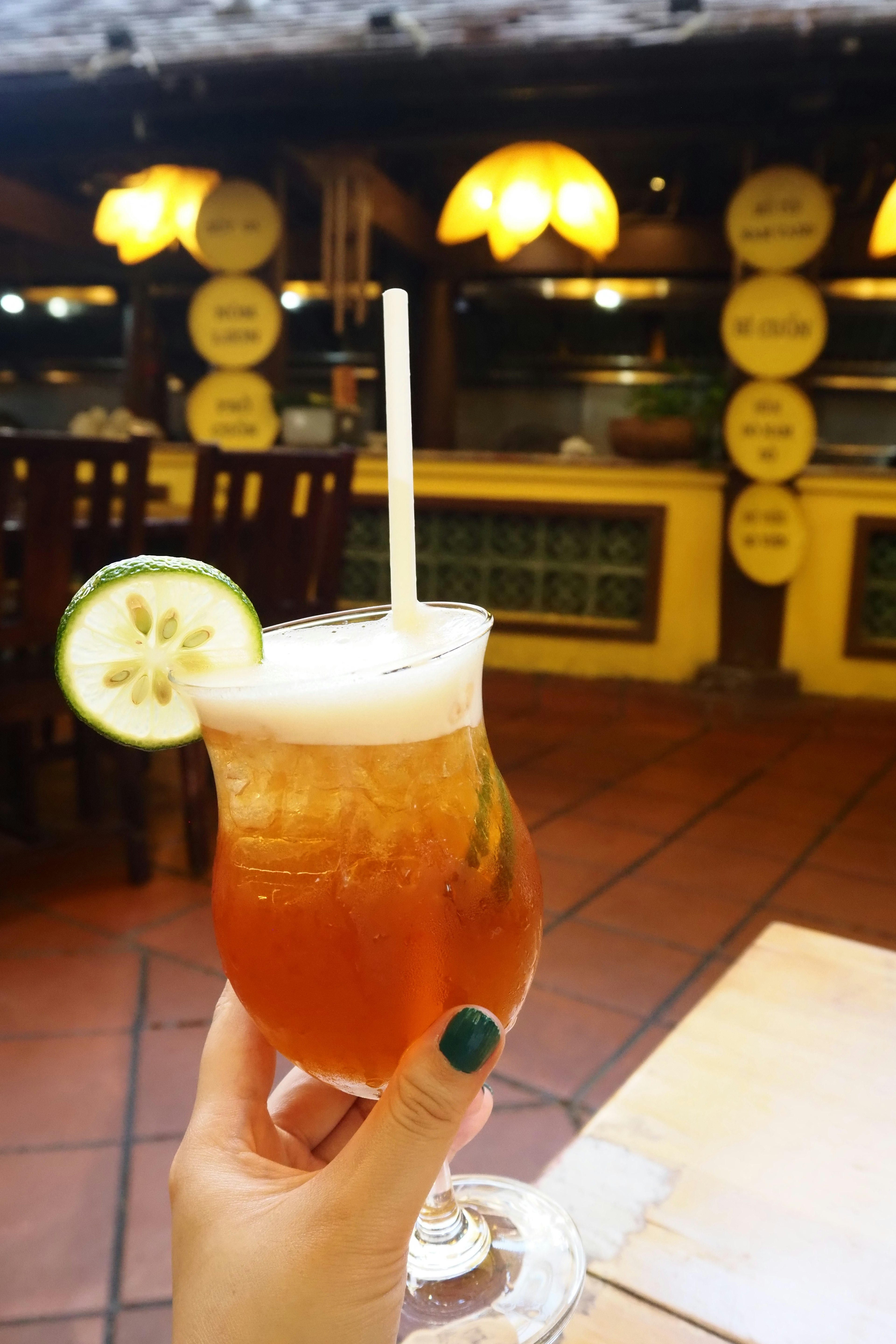 A cocktail glass held in a hand featuring a cucumber slice garnish