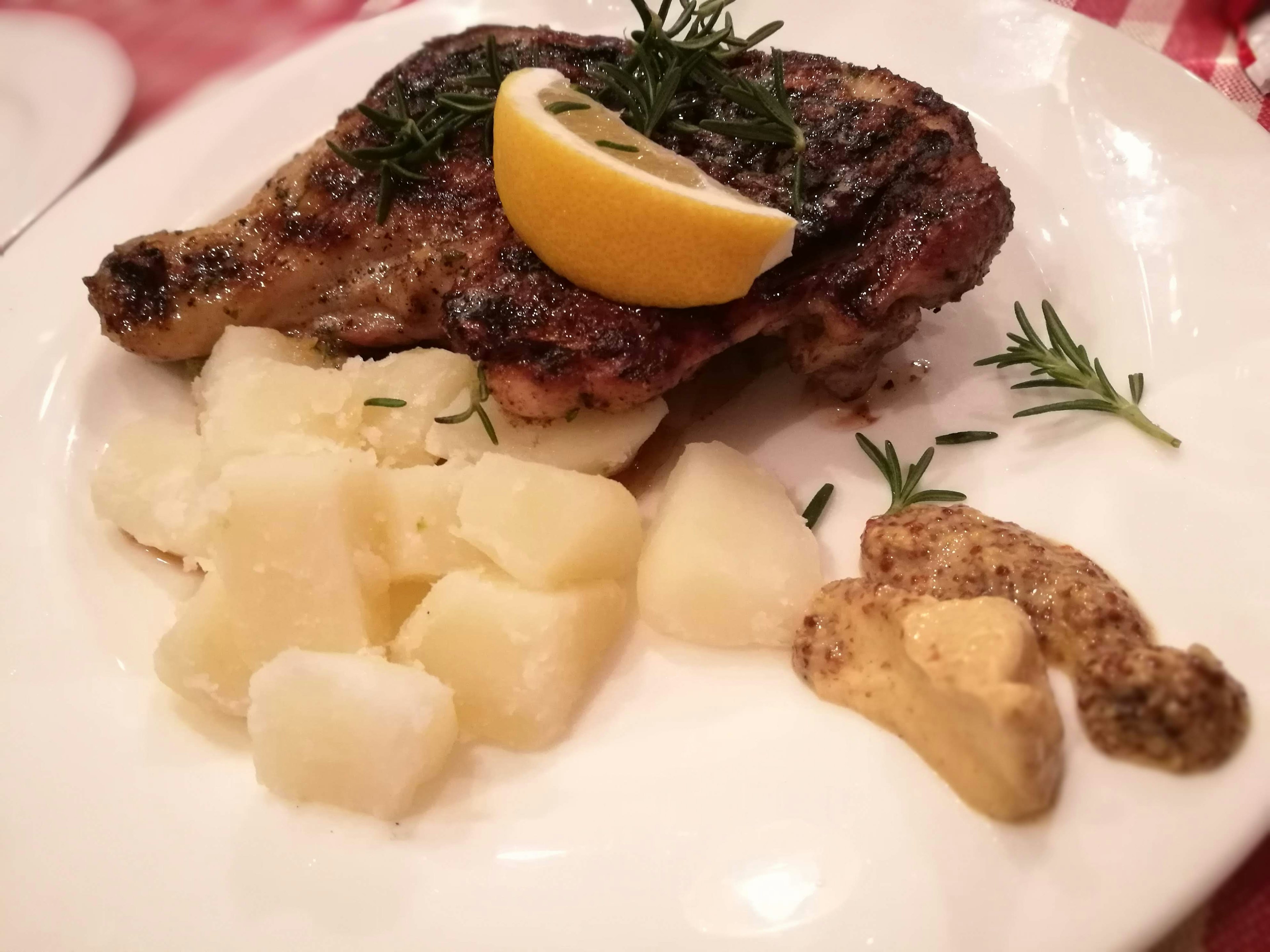 Paha ayam panggang dihias dengan lemon dan rosemary disajikan dengan kentang dan mustard