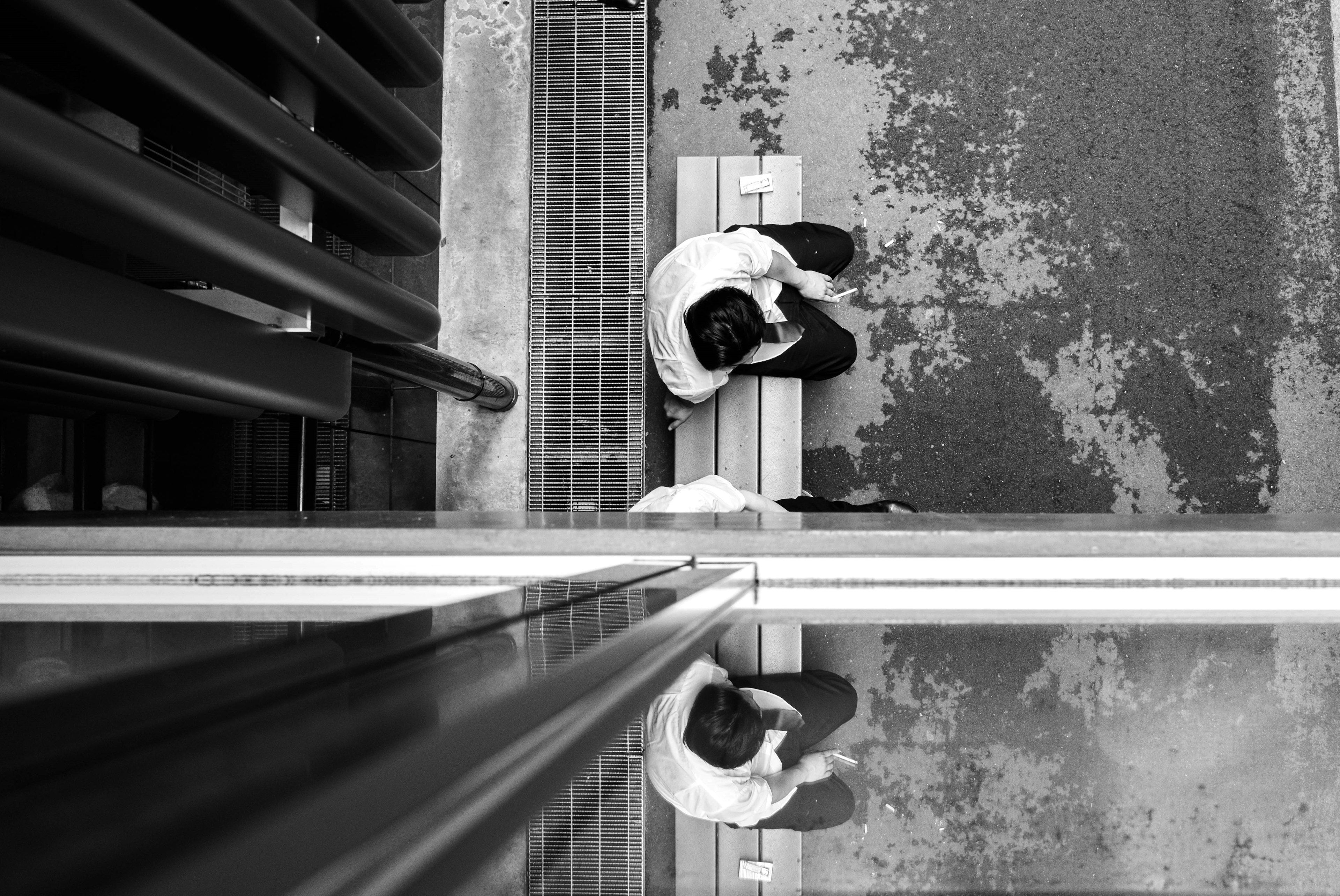 Photo en noir et blanc montrant deux personnes assises sur un banc vue du dessus