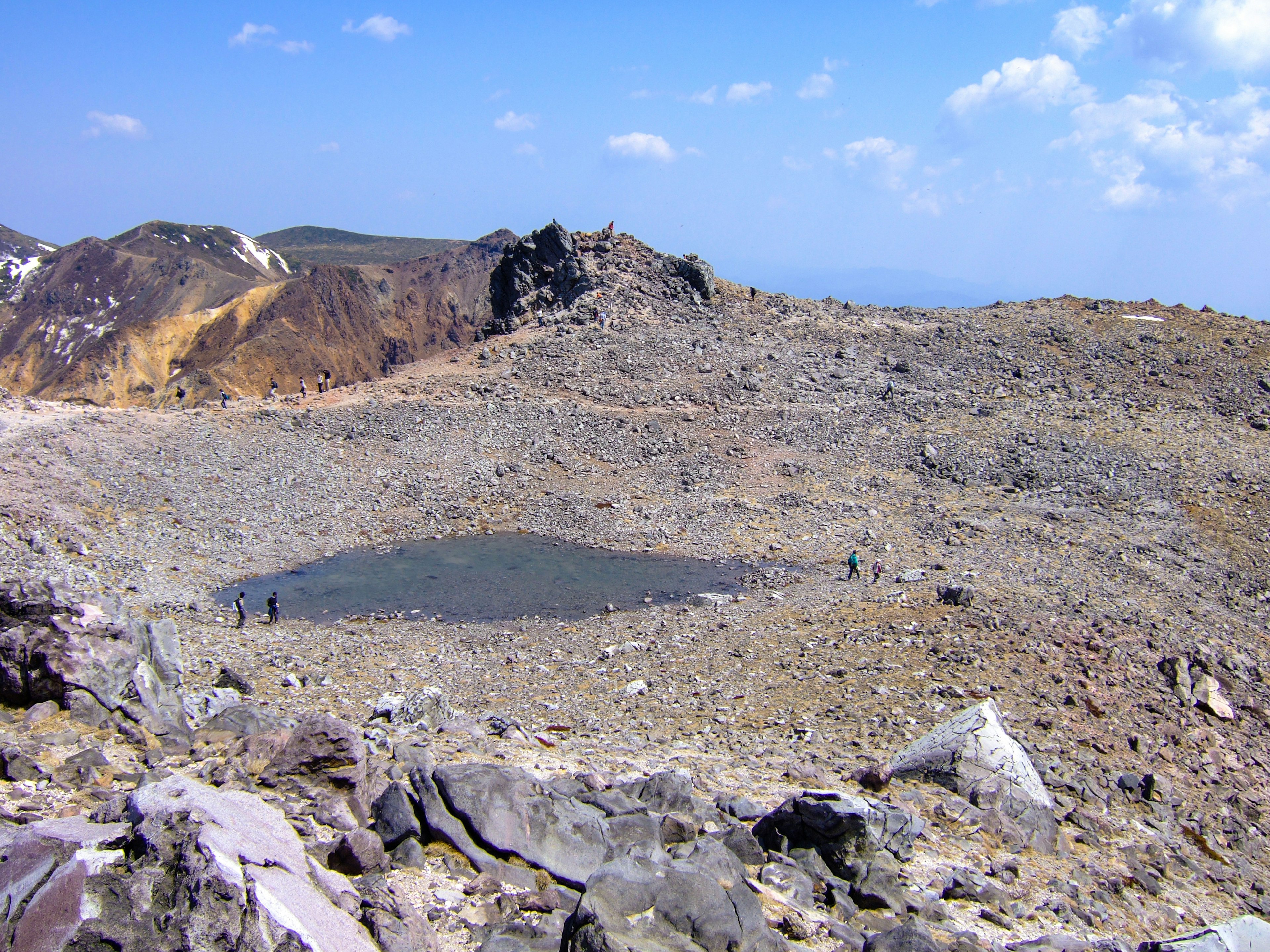 火山のクレーターと小さな水たまりが見える荒れた風景