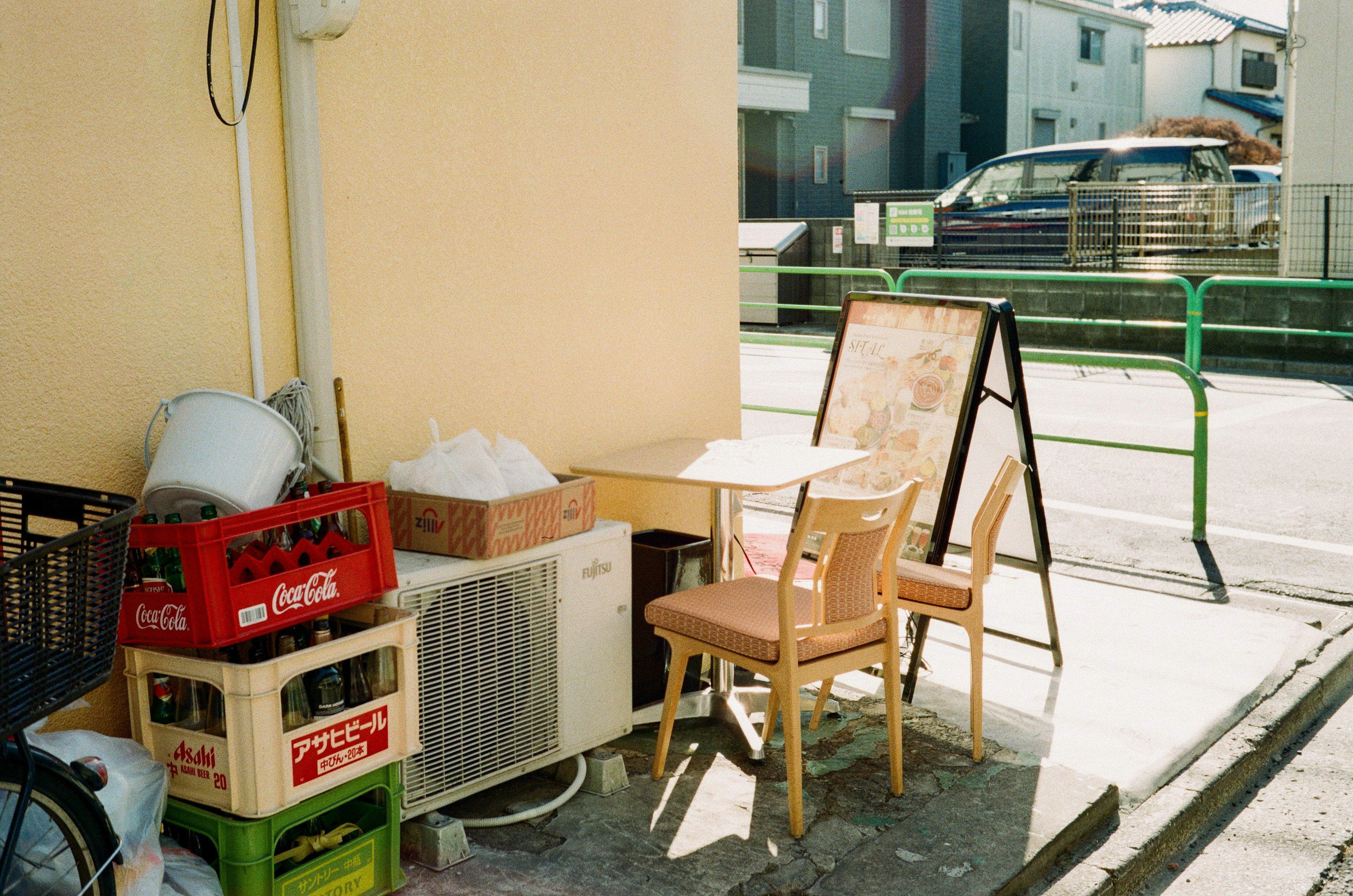 Ensemble table et chaises placé dans une ruelle avec des poubelles et des caisses de boissons à proximité