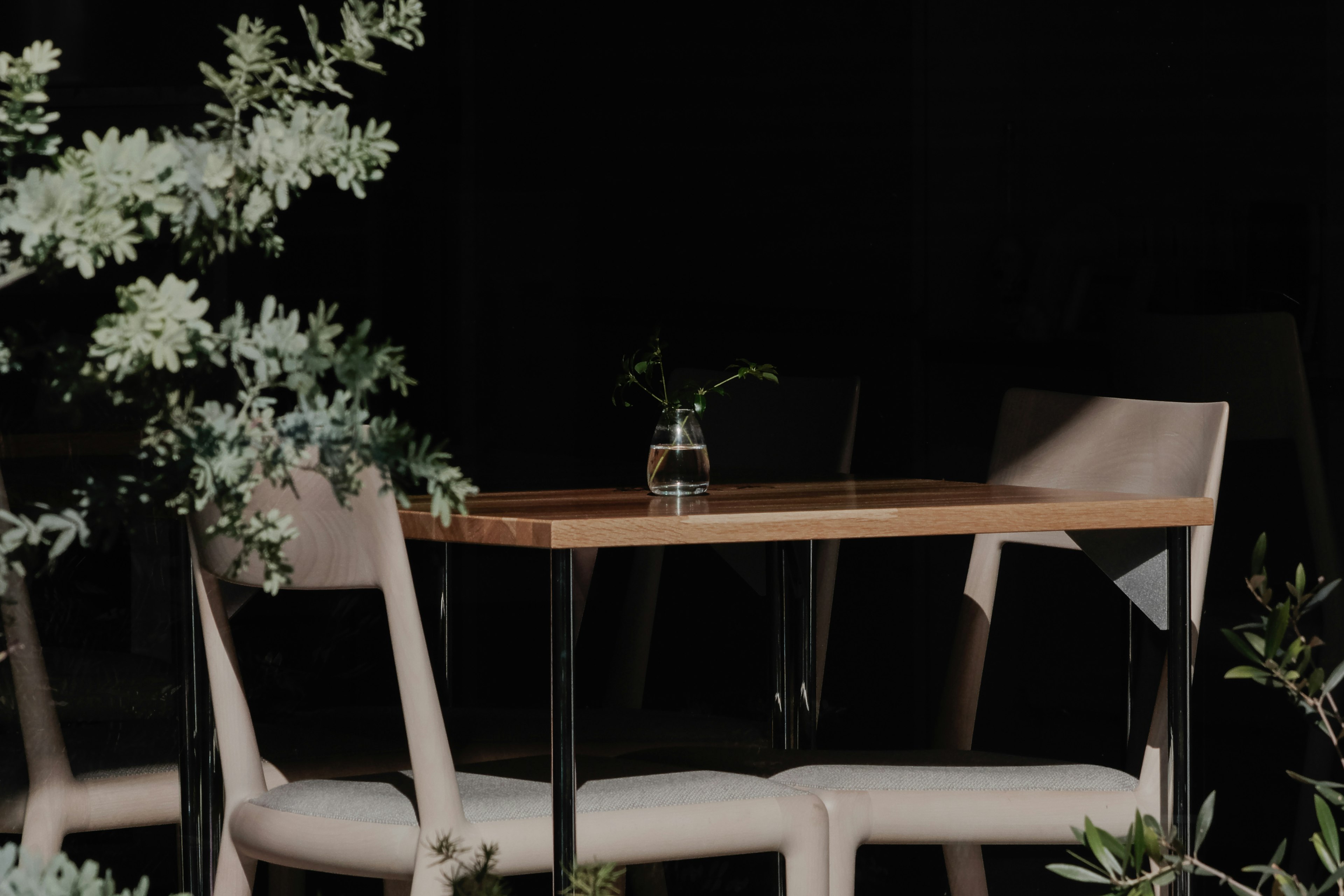 Une table en bois simple avec deux chaises et un petit vase dessus