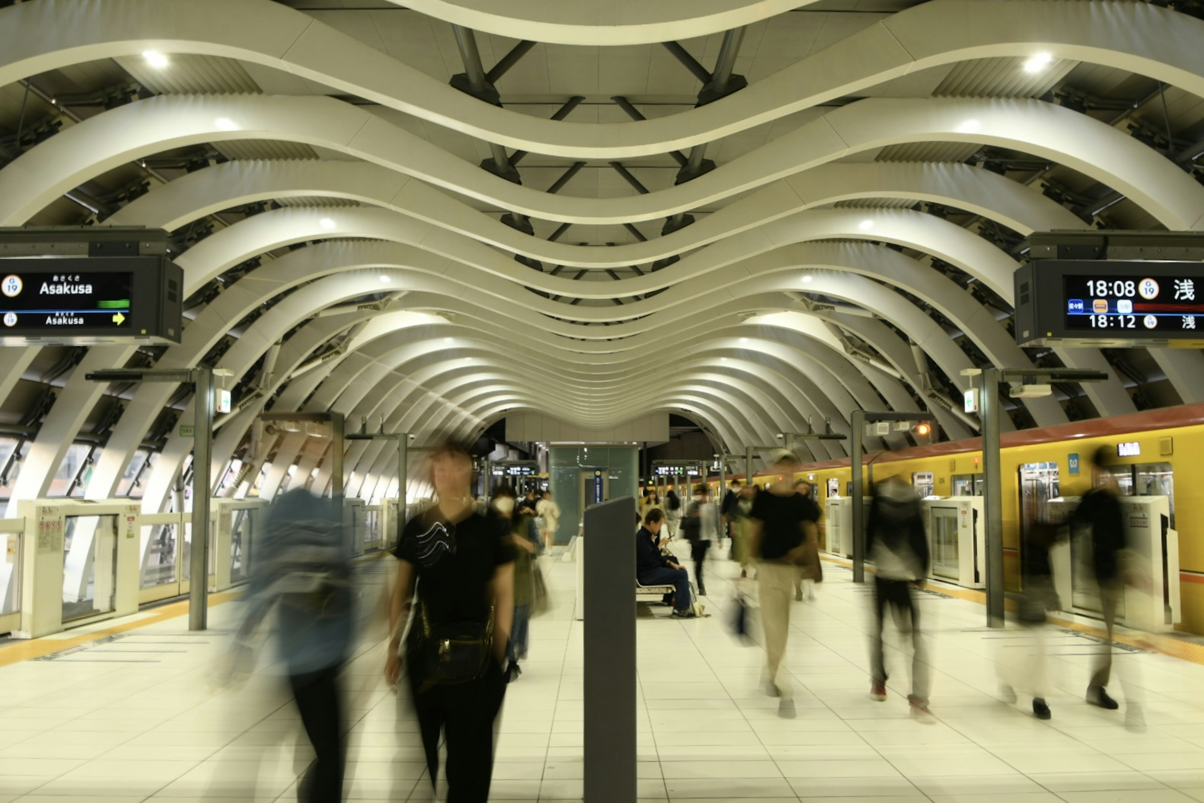 Interior stasiun kereta bawah tanah modern dengan desain langit-langit mengalir dan penumpang yang bergerak