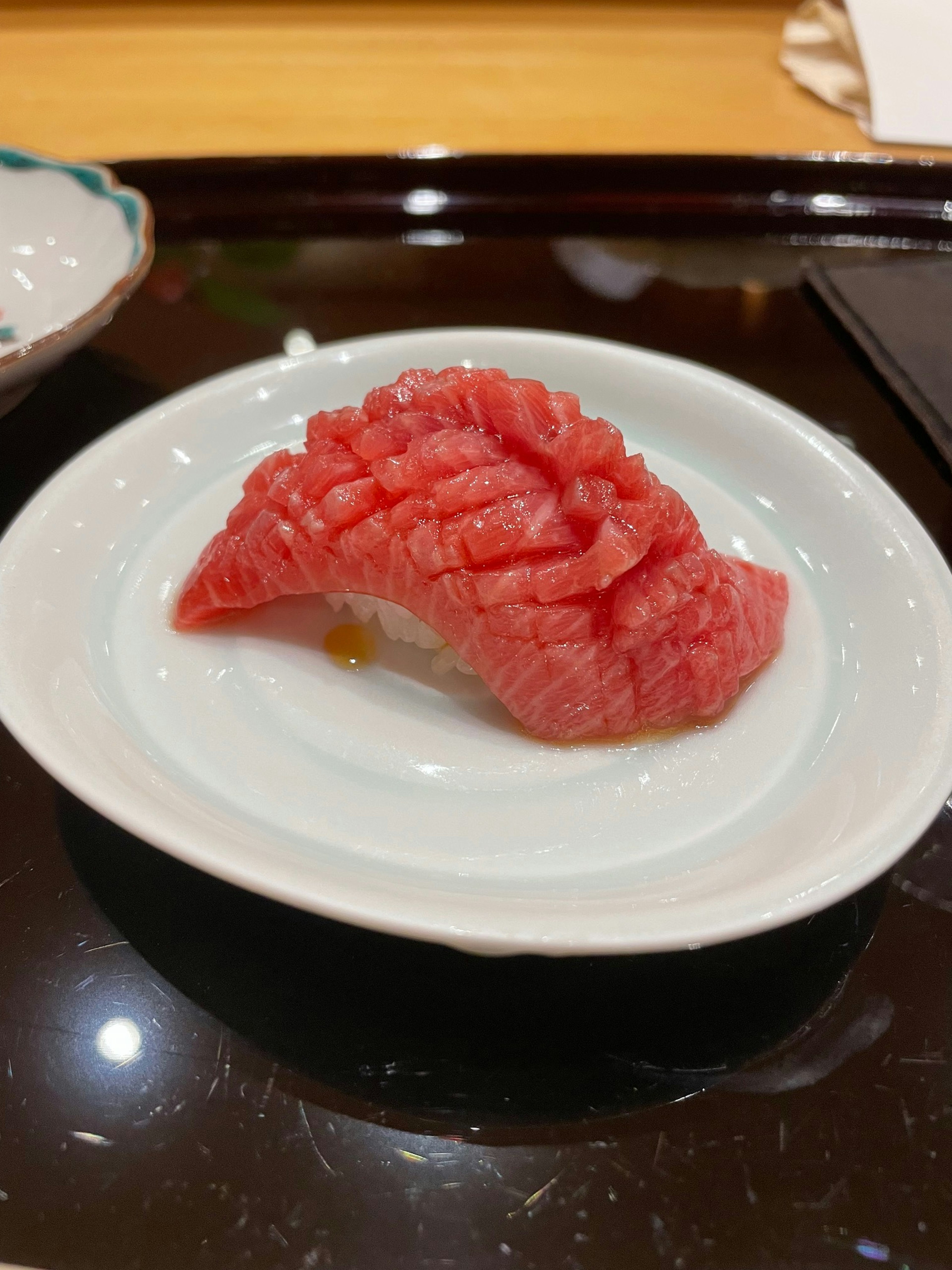 Sushi tuna yang diiris disajikan di atas piring putih