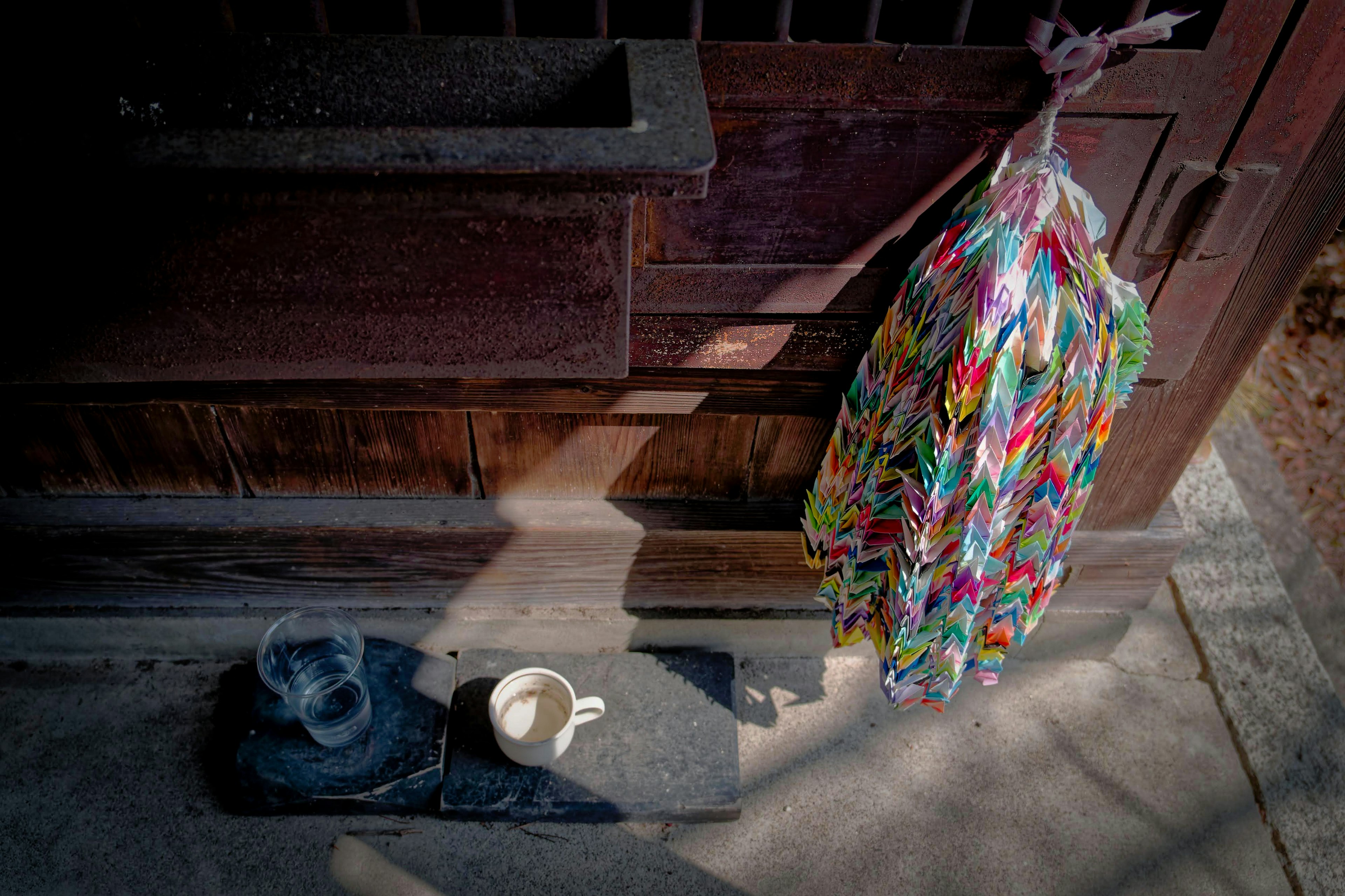 Prenda colorida y taza blanca colocadas frente a una puerta de madera antigua