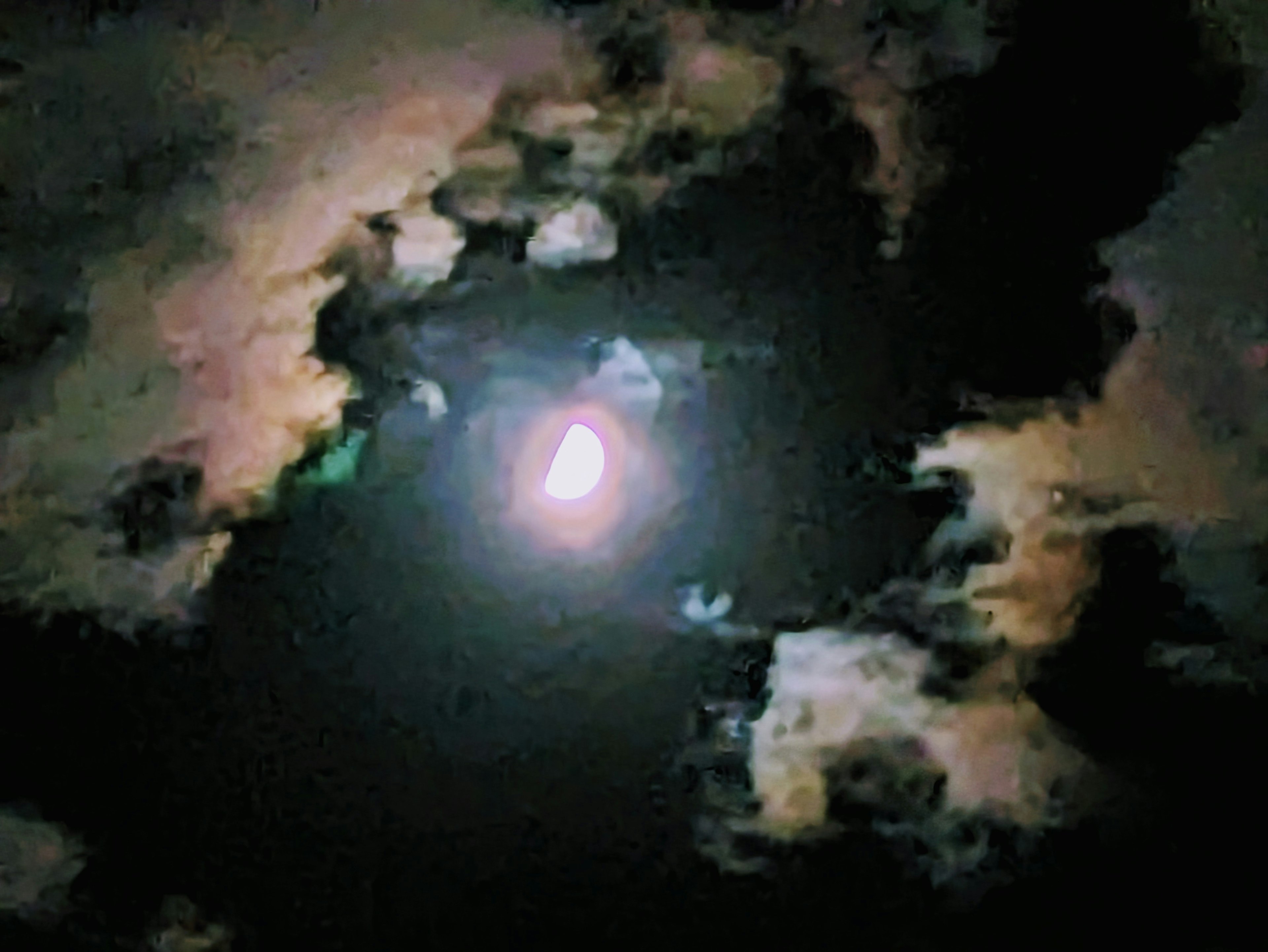 Bright moon shining in a dark sky surrounded by clouds