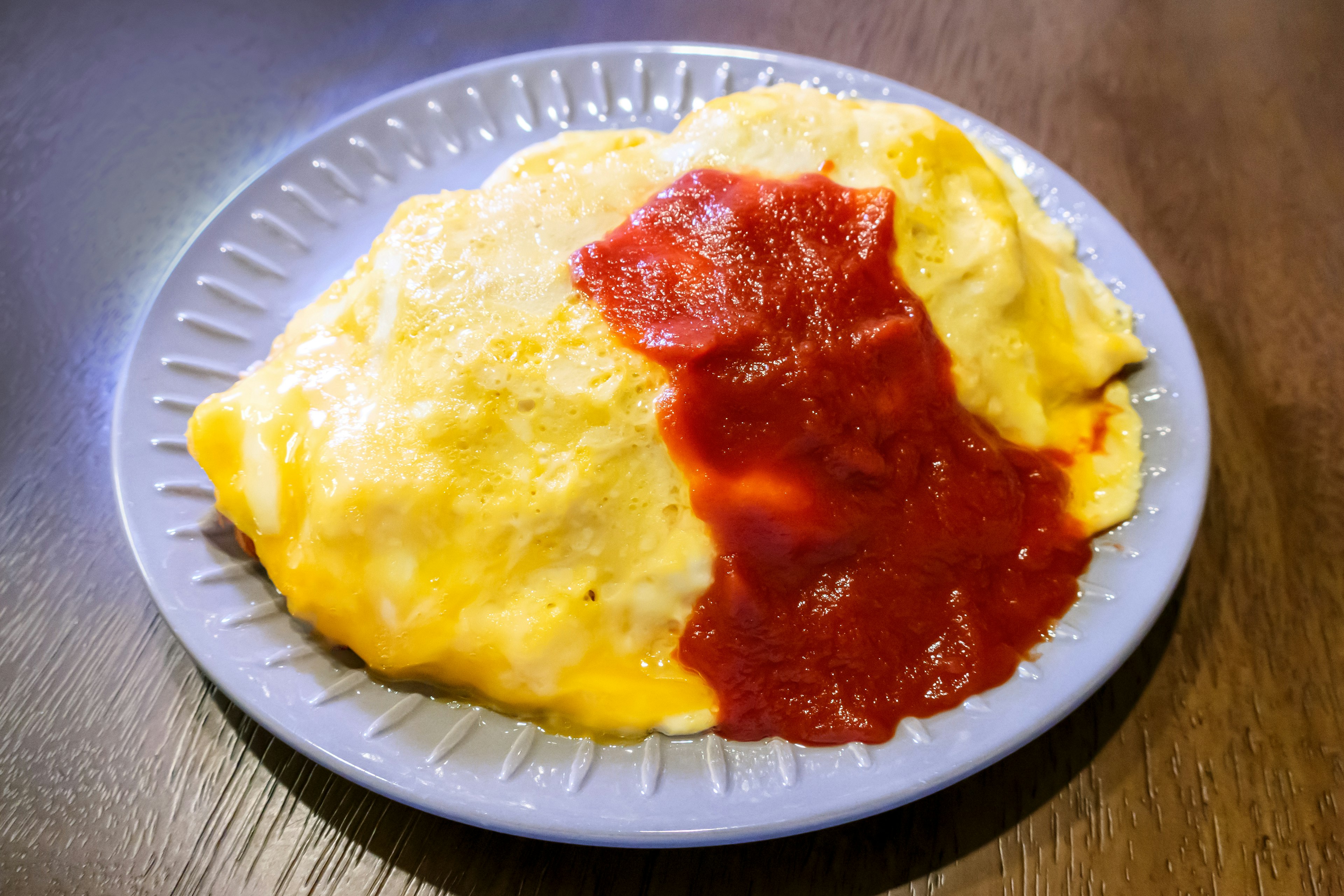 Nasi omelet disajikan di piring dengan saus tomat