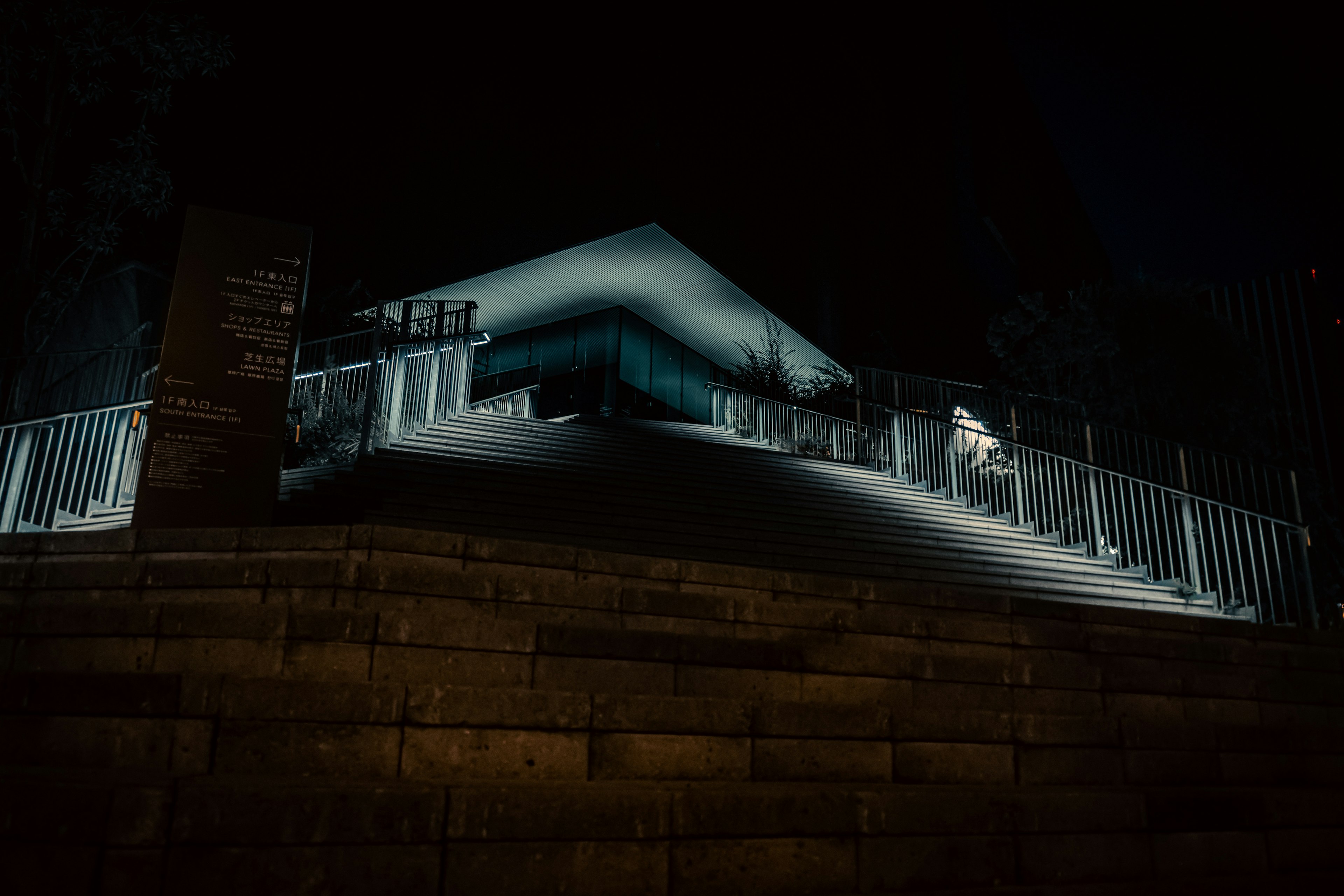 Edificio blanco iluminado por la noche con una escalera y una cerca brillante