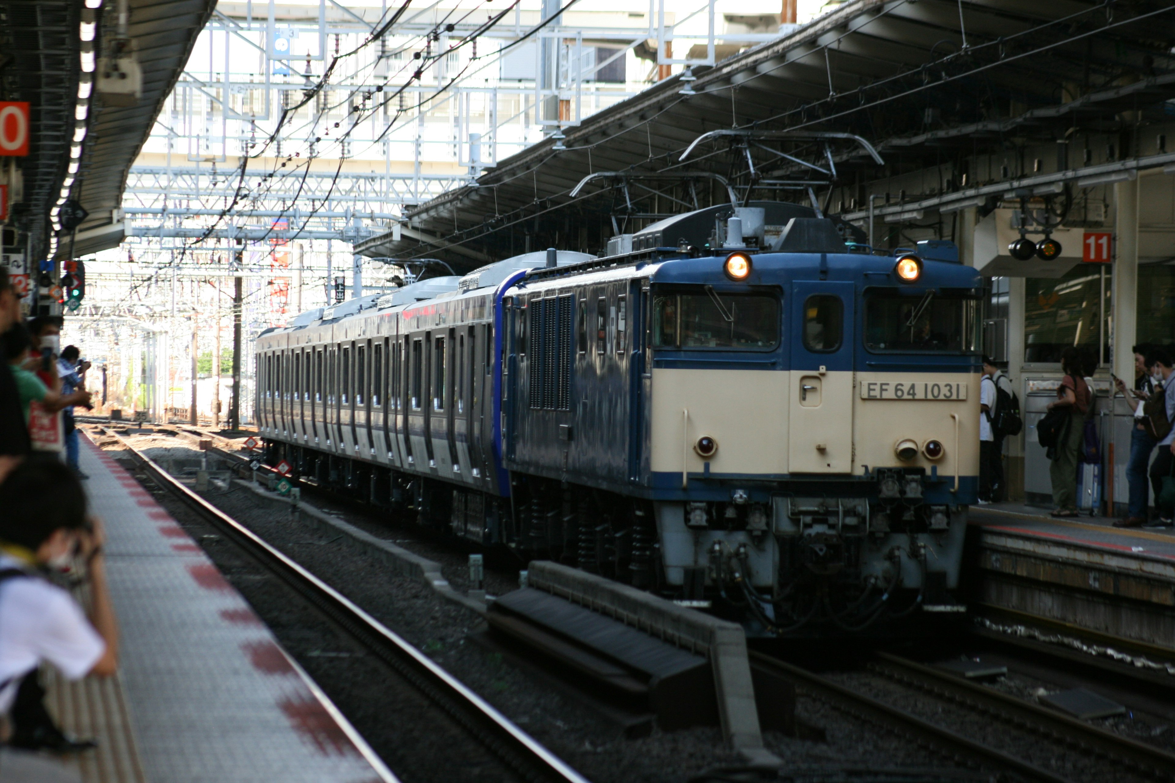 รถไฟสีน้ำเงินมาถึงสถานีพร้อมโครงสร้างที่มองเห็นได้