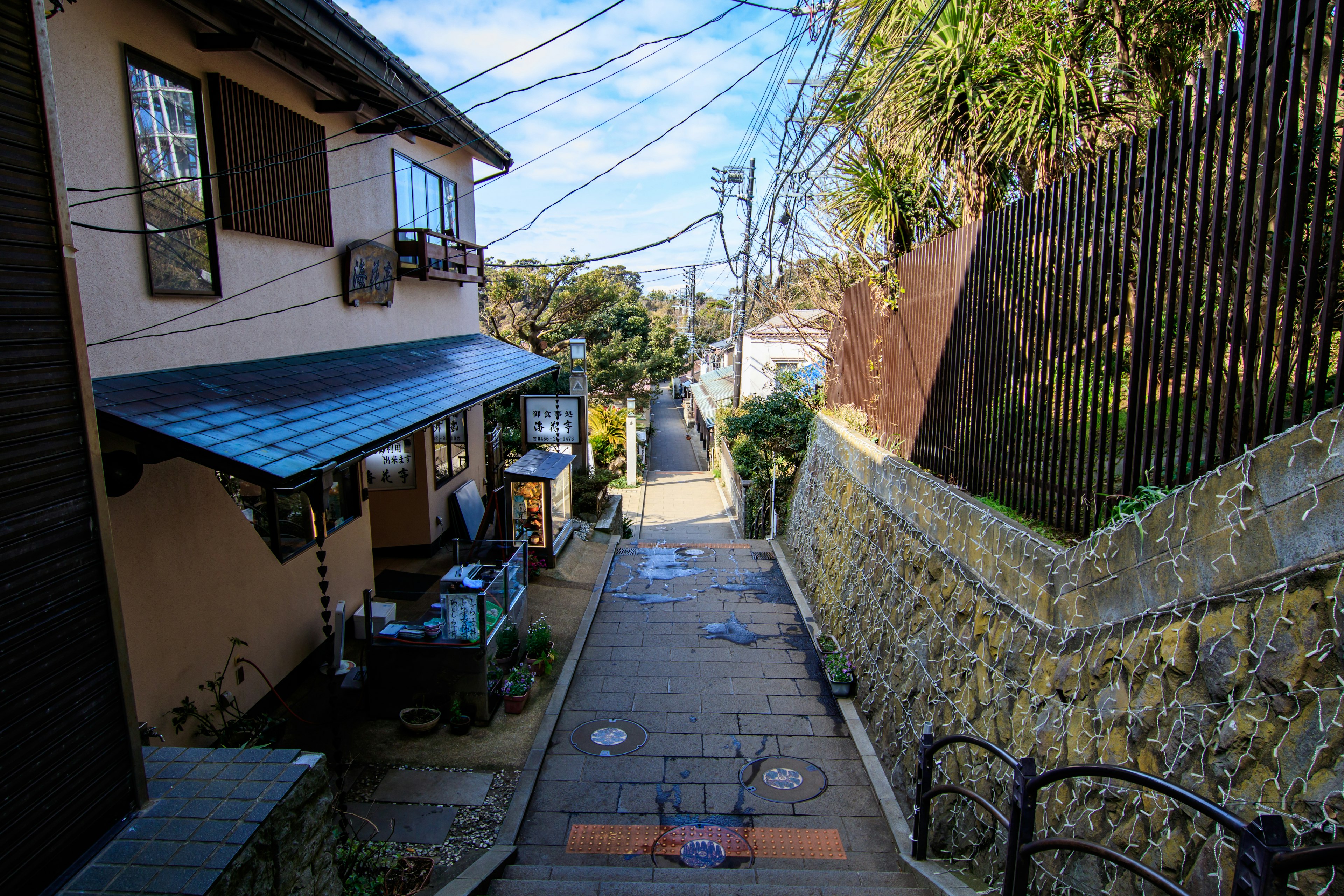 Narrow path with houses lined along it under a blue sky with power lines