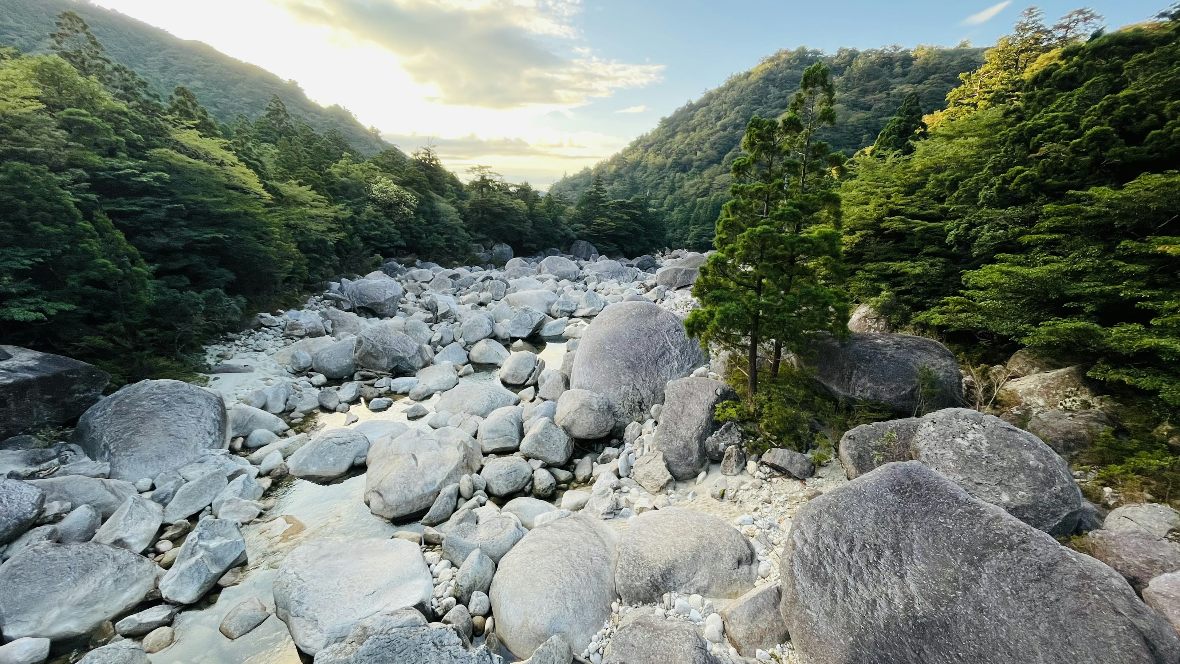 A riverbed surrounded by lush mountains and large boulders