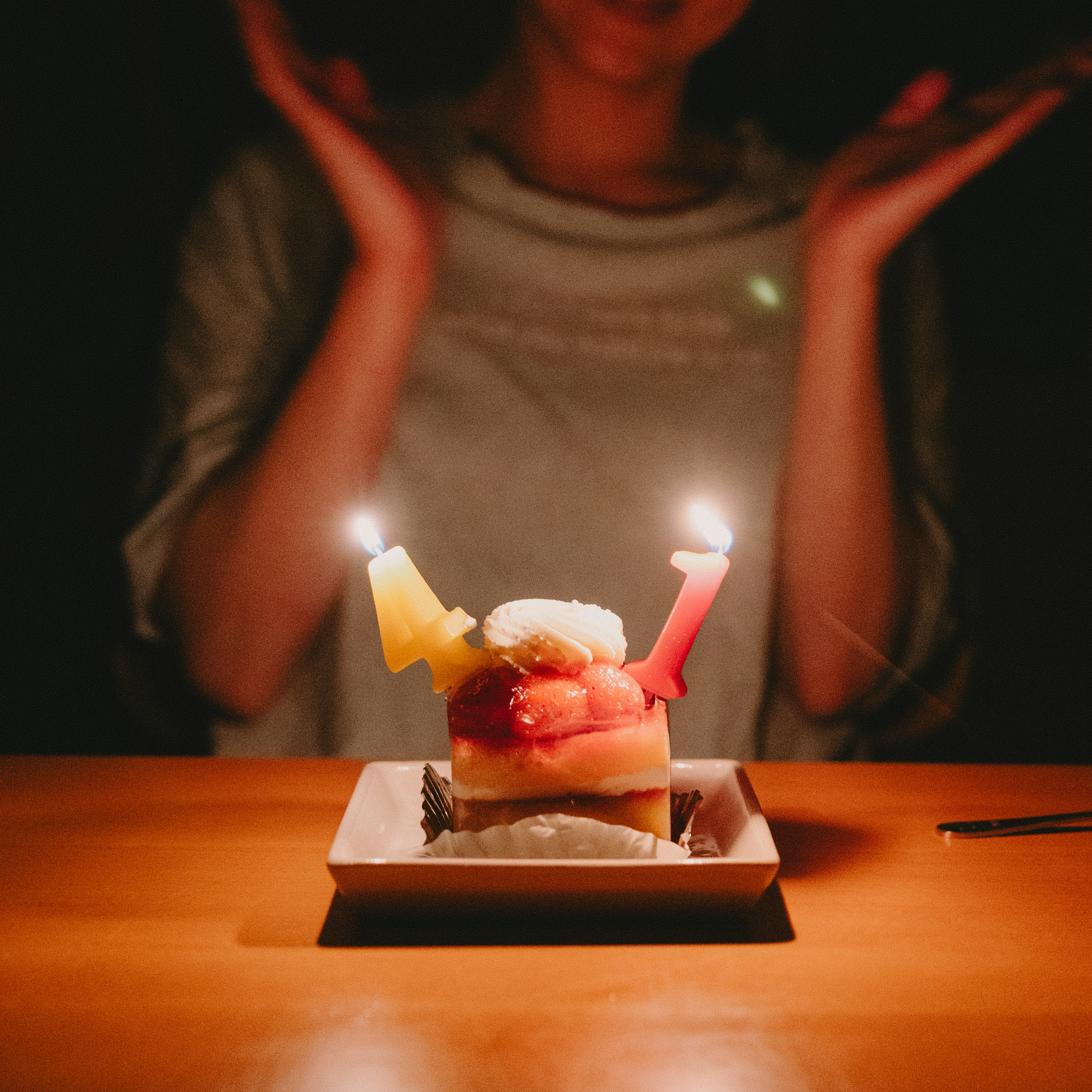 Person celebrating with a cake and candles in a dim setting