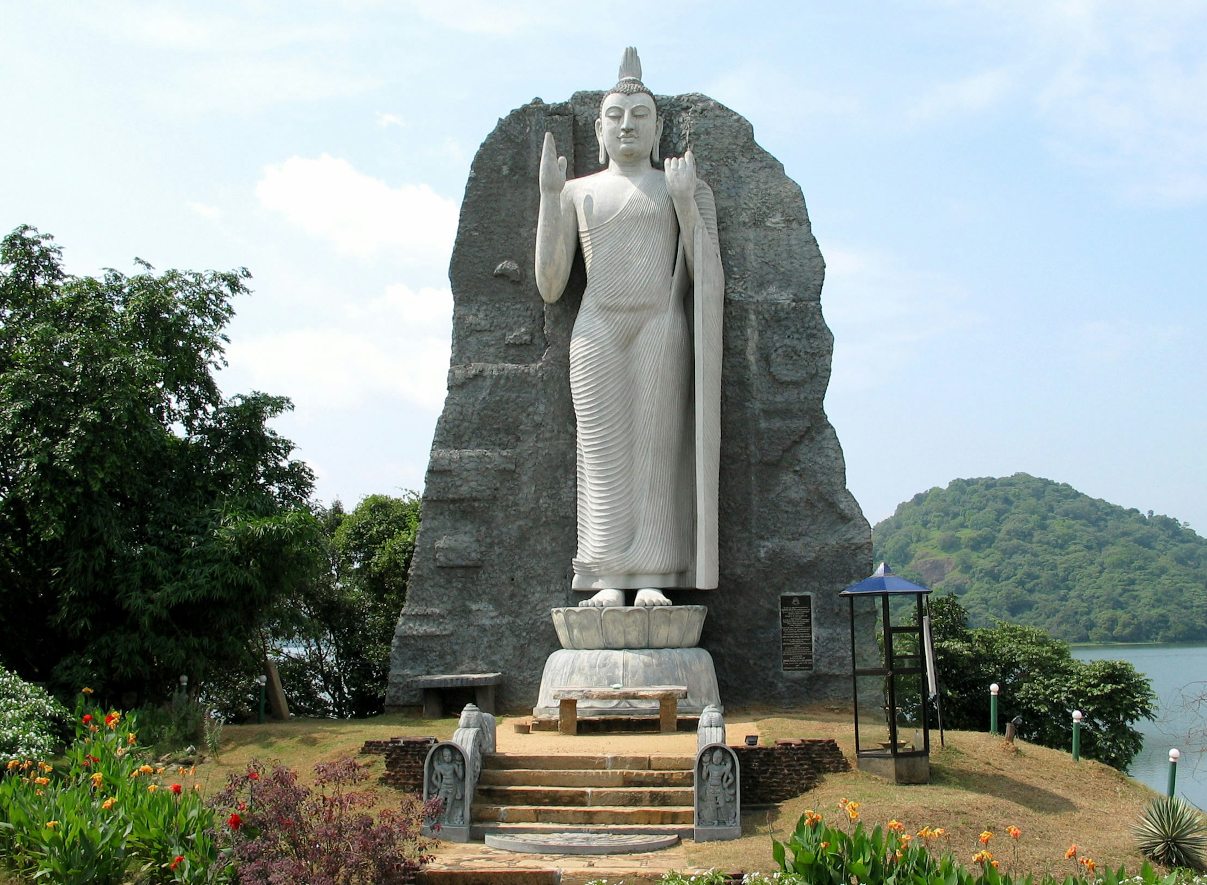 Large Buddha statue standing in front of a rock formation