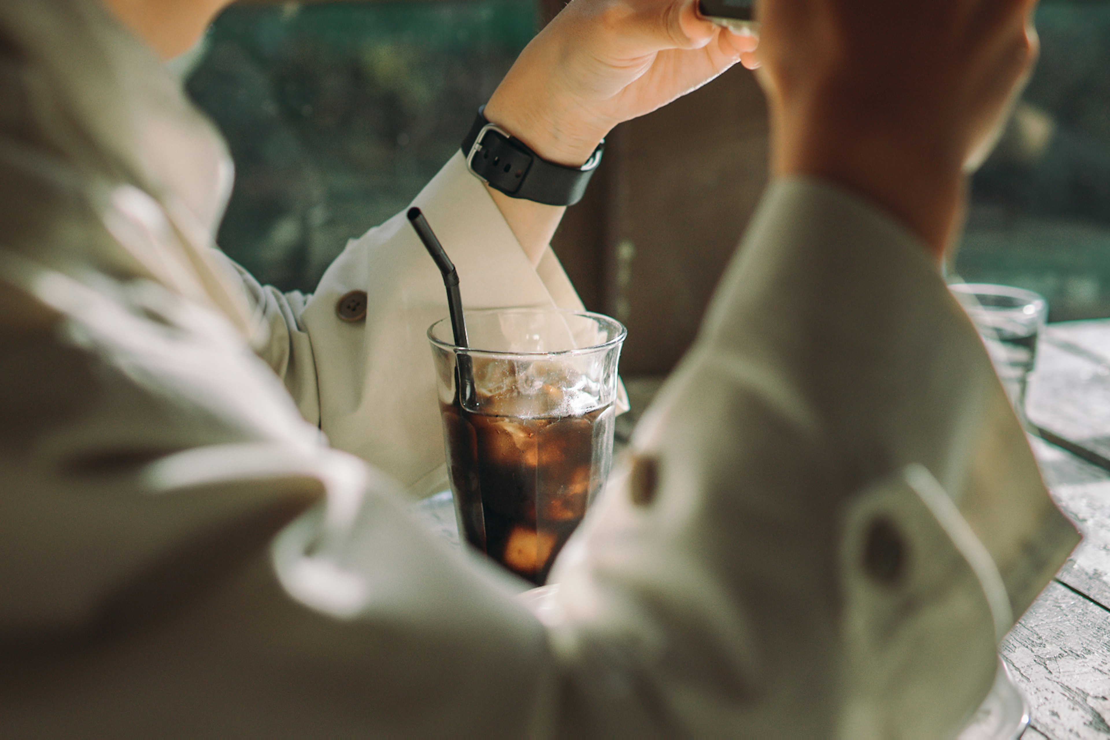 Primer plano de una persona sosteniendo café helado con un reloj elegante