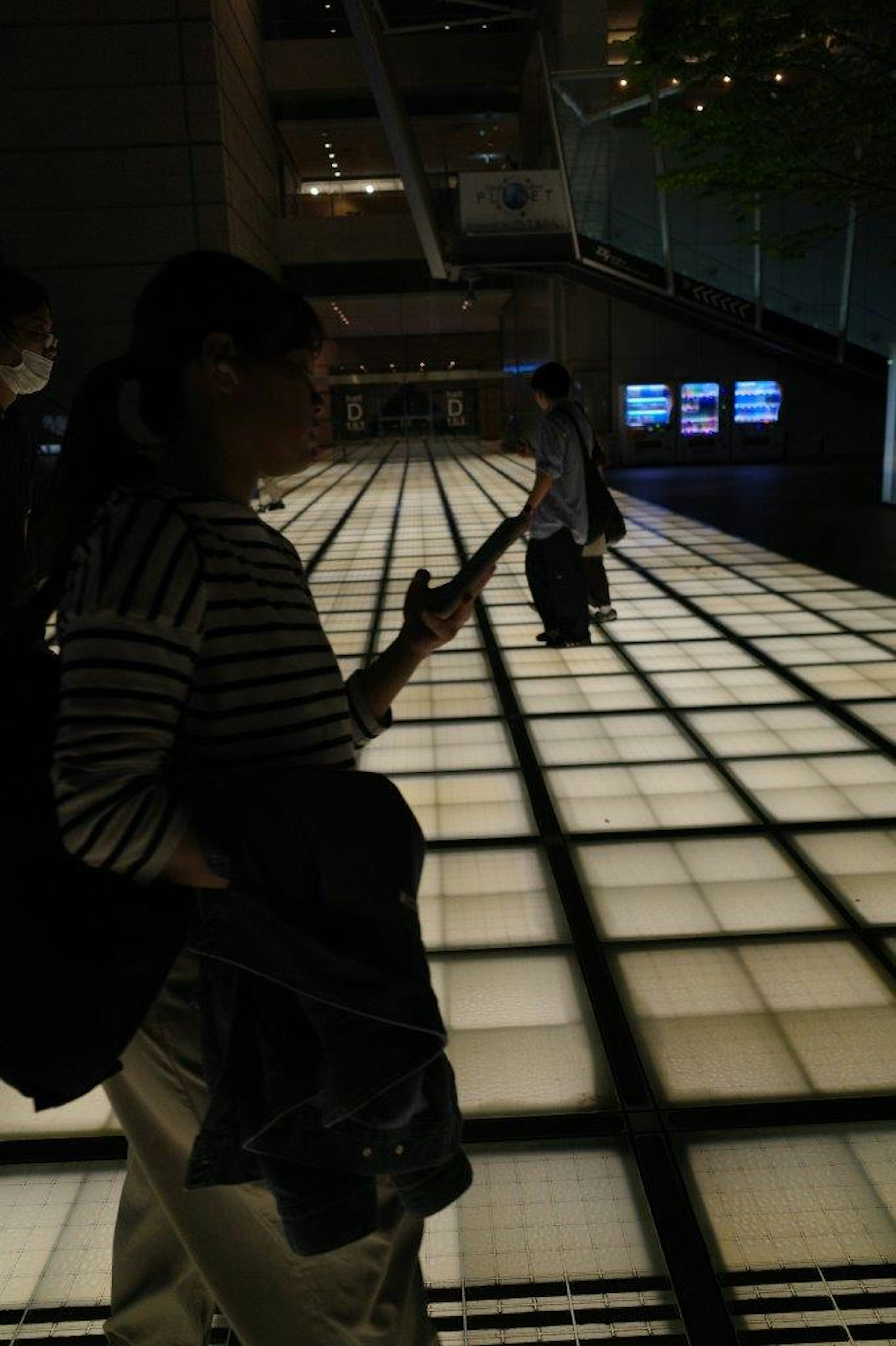 Silhouette of a person standing on a brightly lit floor in an urban night scene