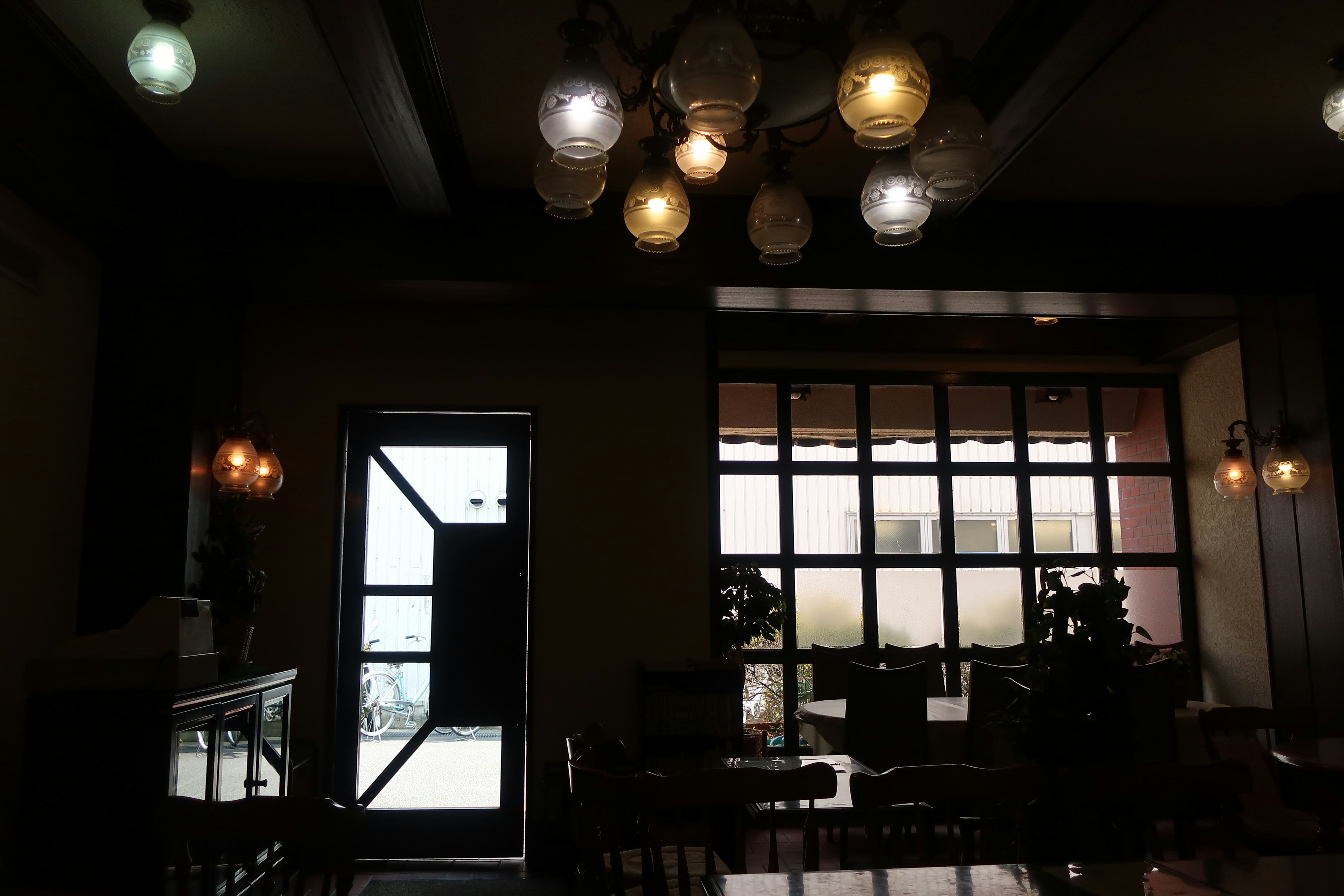 Interior de una cafetería con iluminación brillante y luz natural que entra por las ventanas