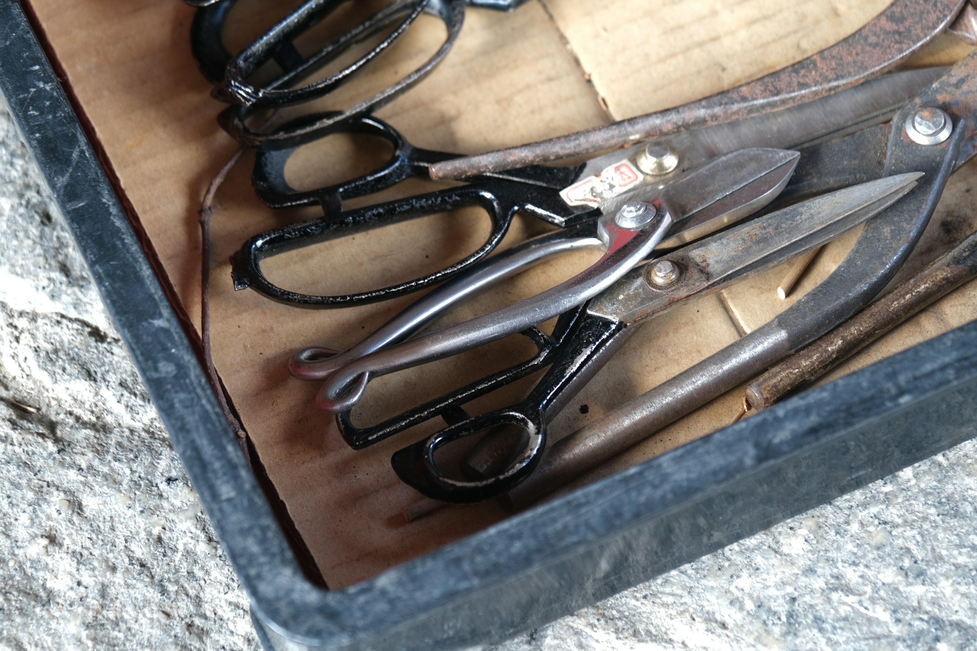 A collection of black scissors and metal tools in a box