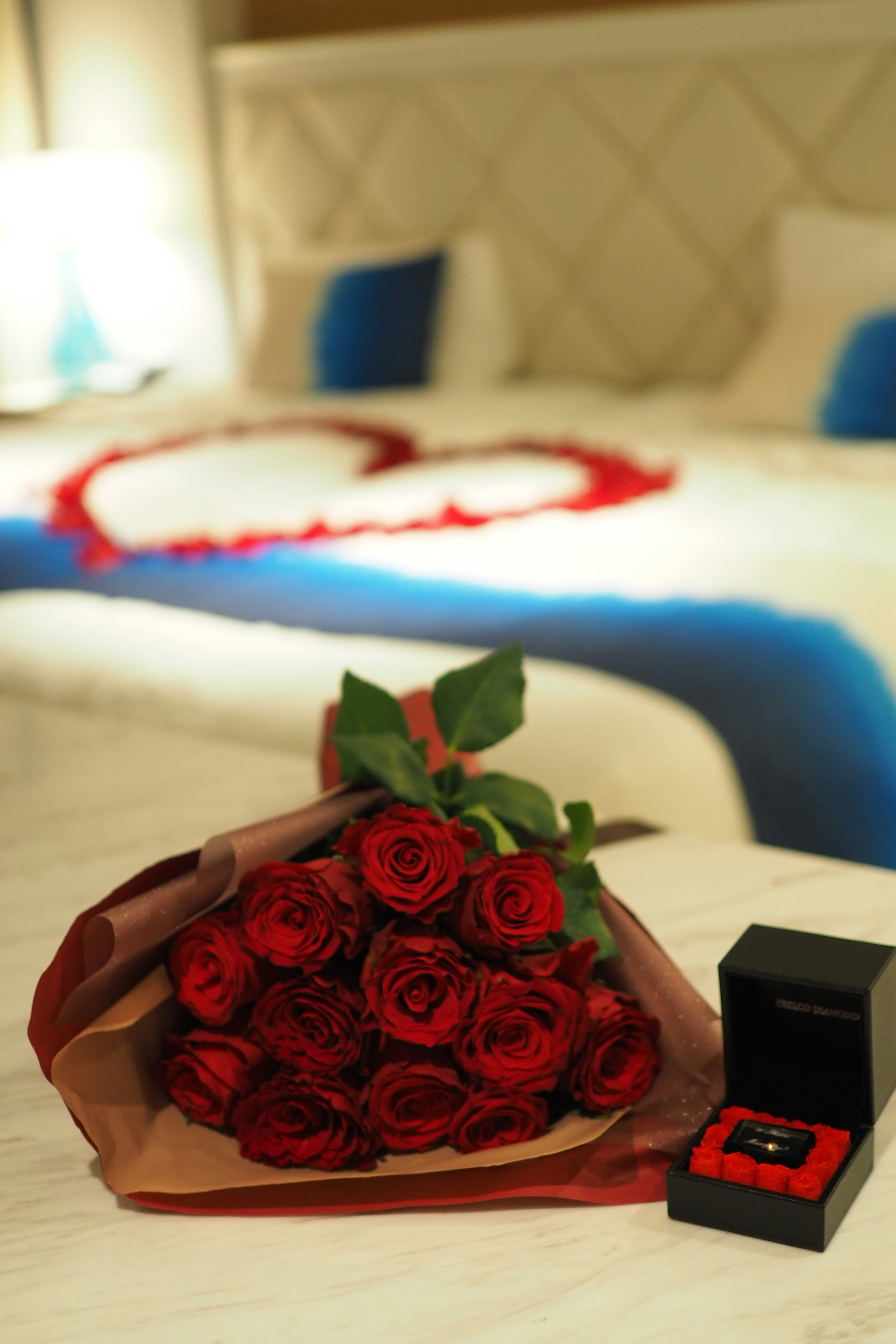 Una habitación de hotel romántica con un ramo de rosas rojas y una caja de anillo