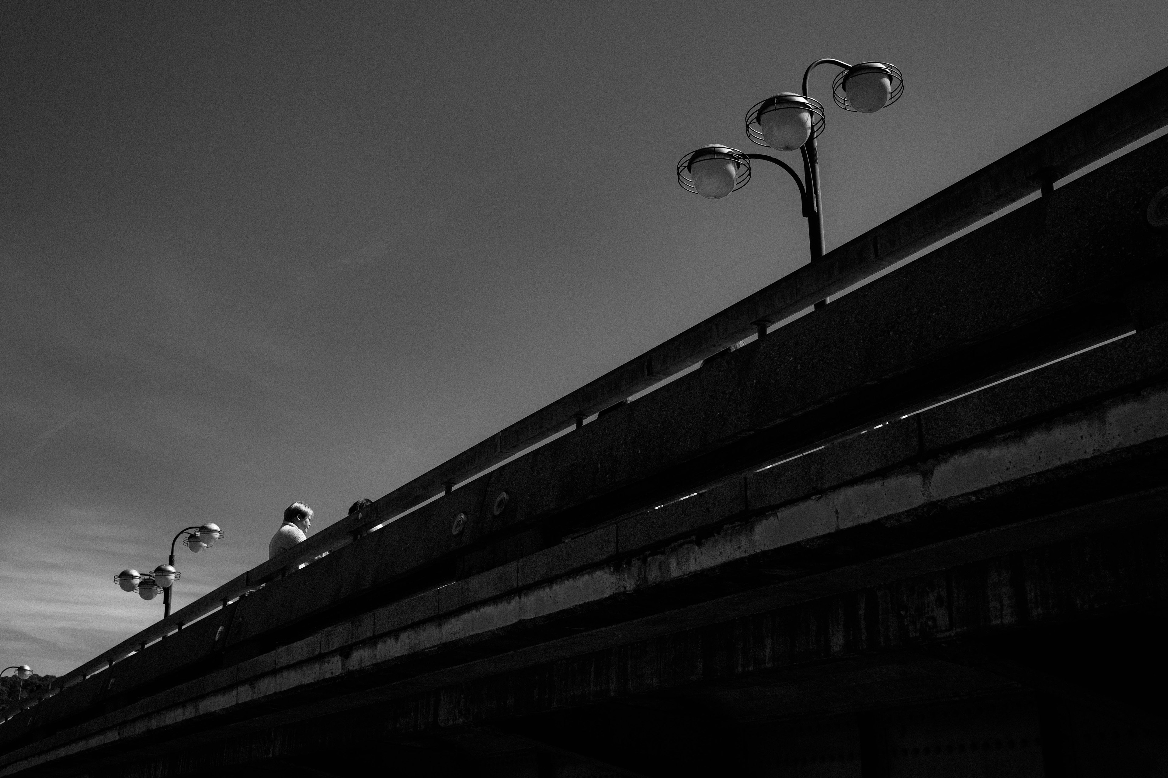 Imagen en blanco y negro de farolas en un puente con sombras