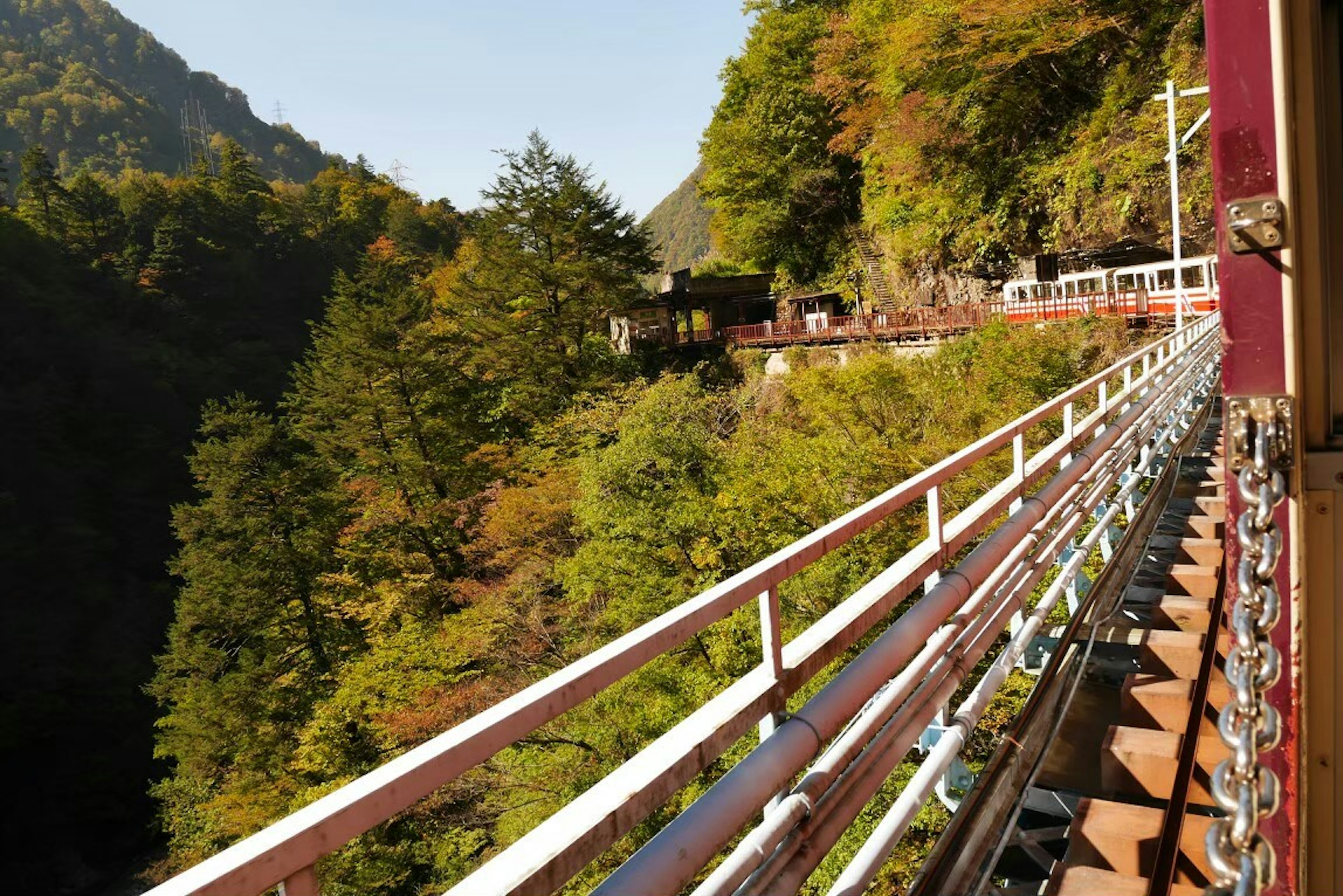 風景如畫的火車景觀，背景是郁郁蔥蔥的山脈和秋季樹葉