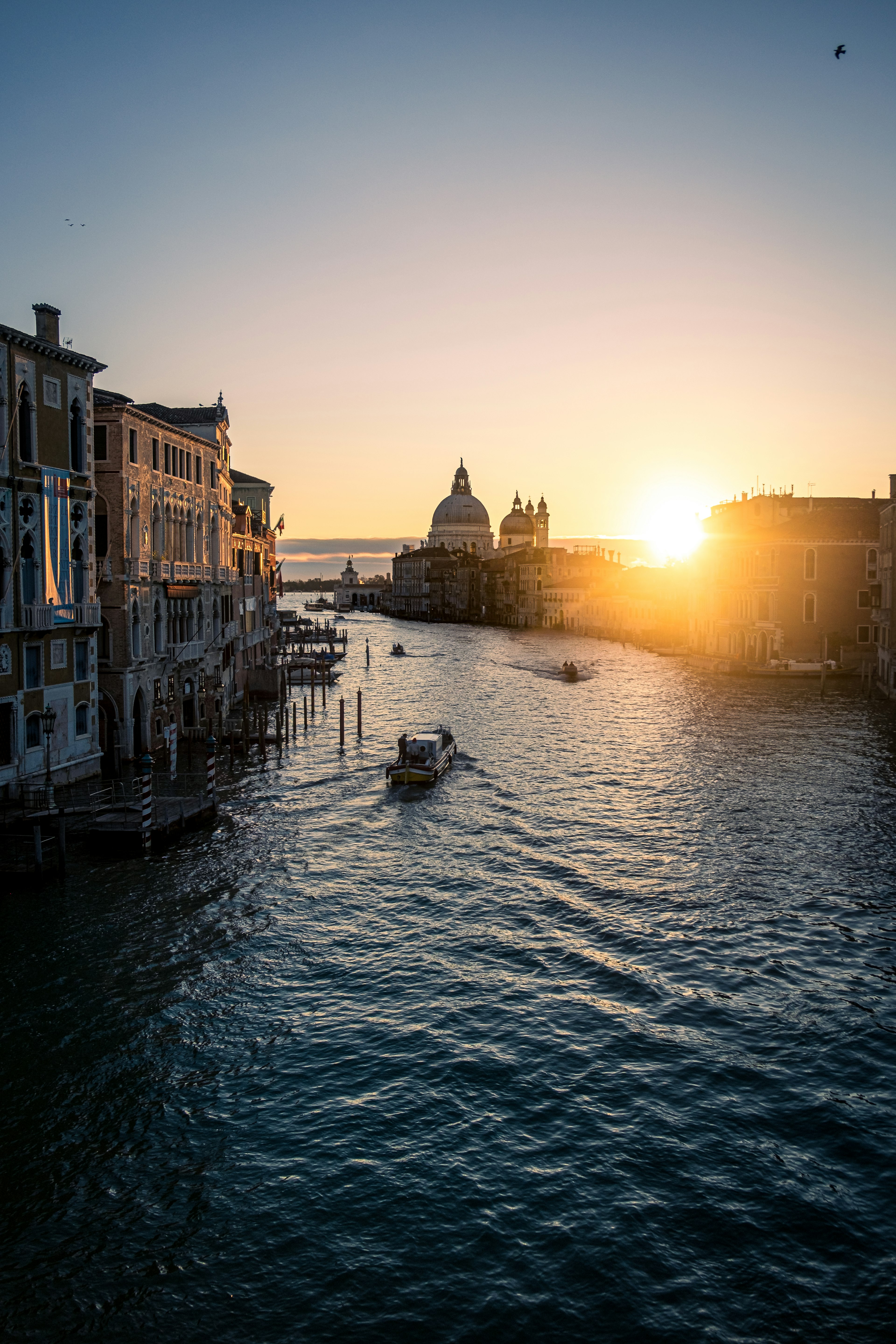 Canale di Venezia al tramonto con barche e edifici storici