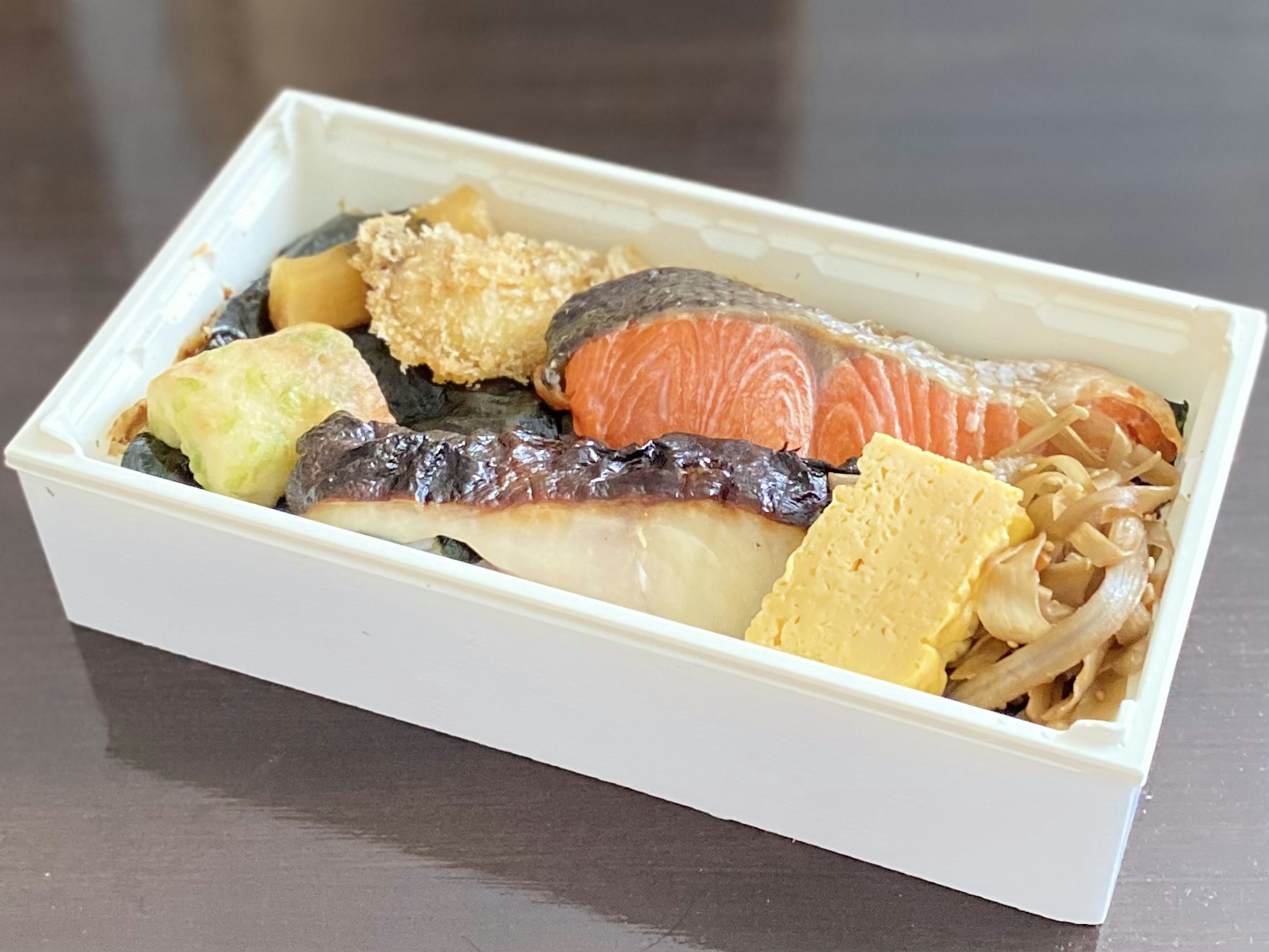 Auswahl an Sushi und Fischgerichten in einer weißen Bentobox