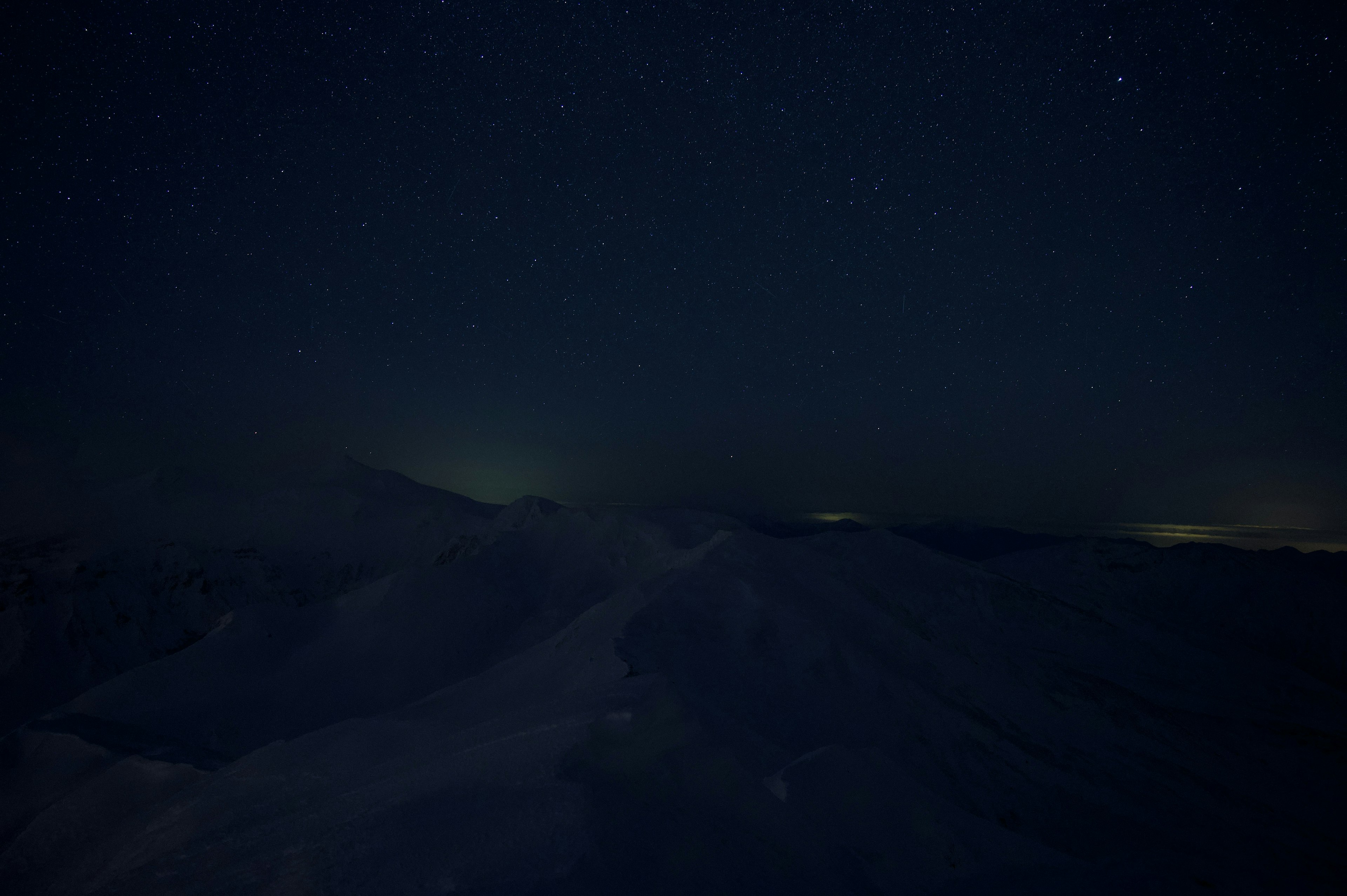 Starry night sky over dark mountain silhouettes