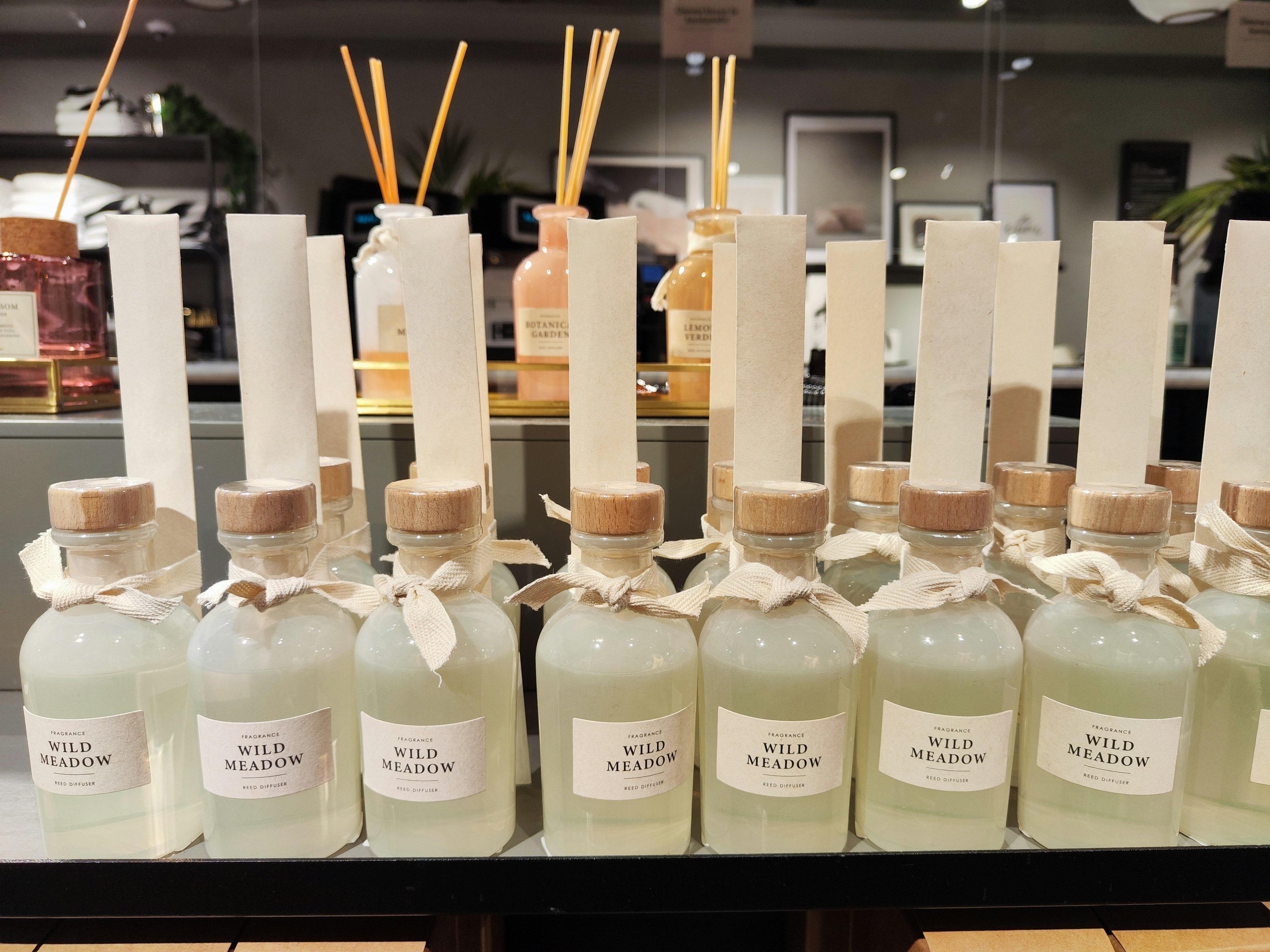 Display of glass bottles with green liquid and white labels arranged on a shelf