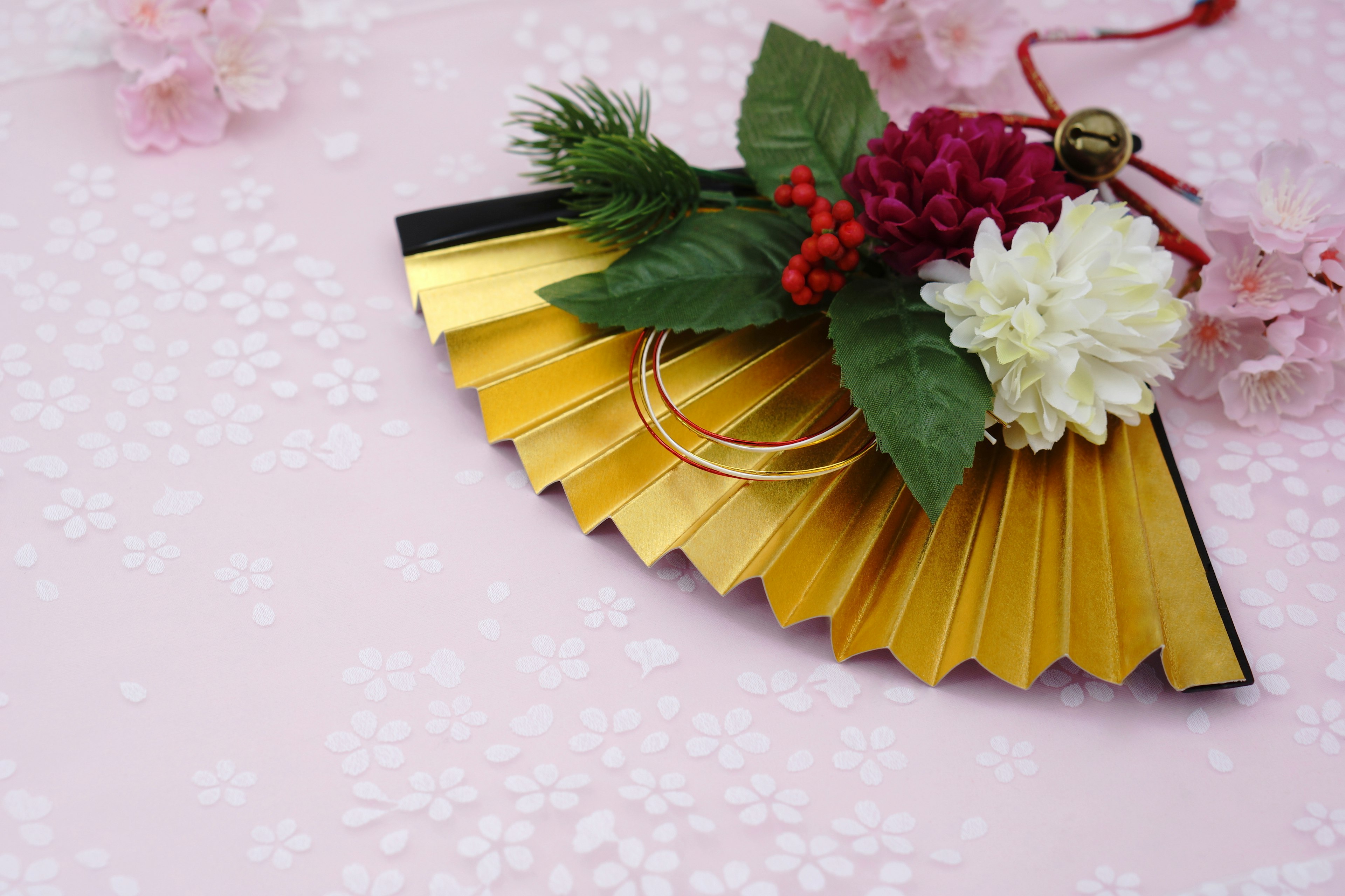 Beautiful arrangement of a golden fan adorned with red berries and white flowers