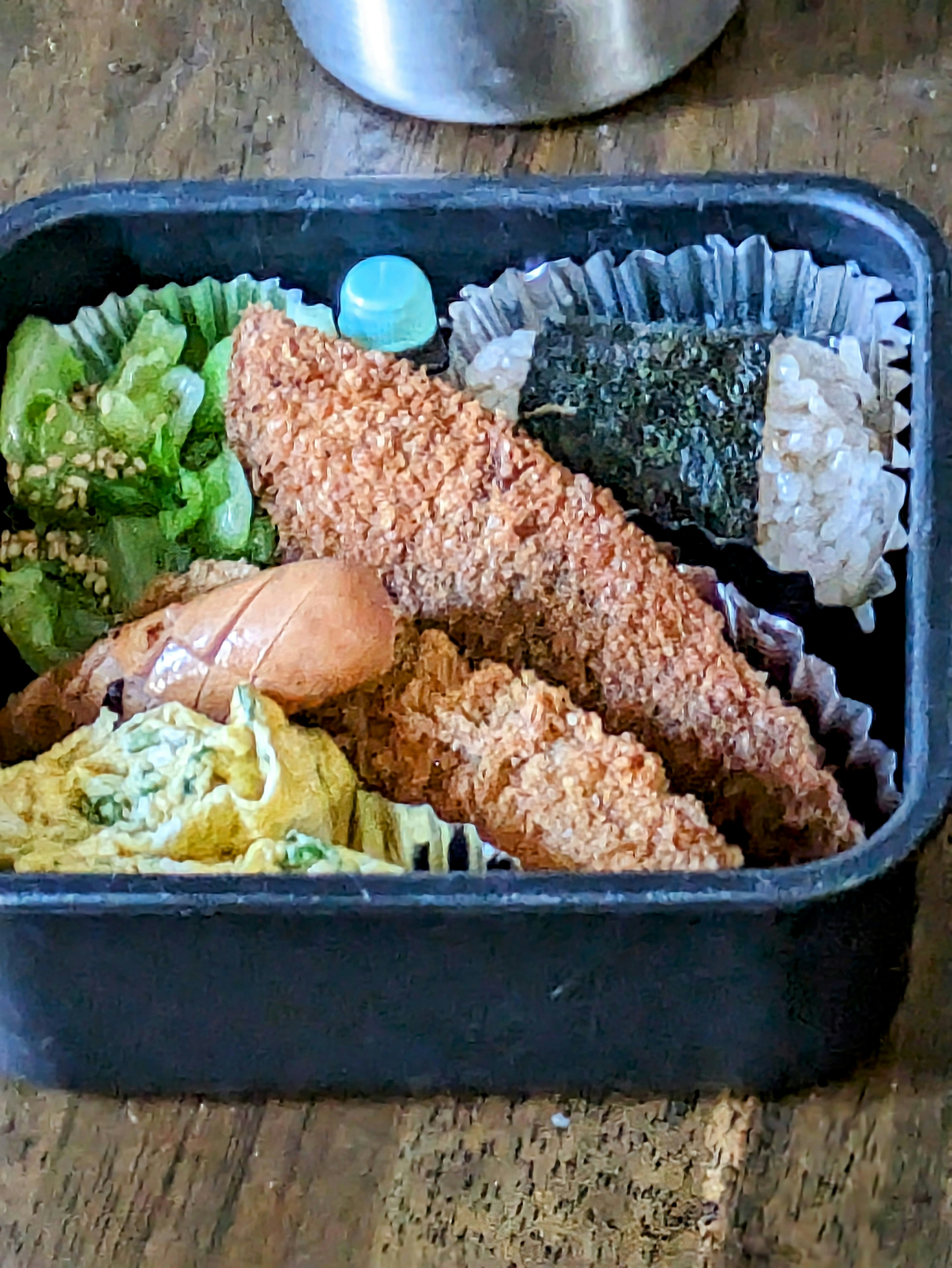 Bento box containing fried fish, tamagoyaki, seaweed, green vegetables, and white rice