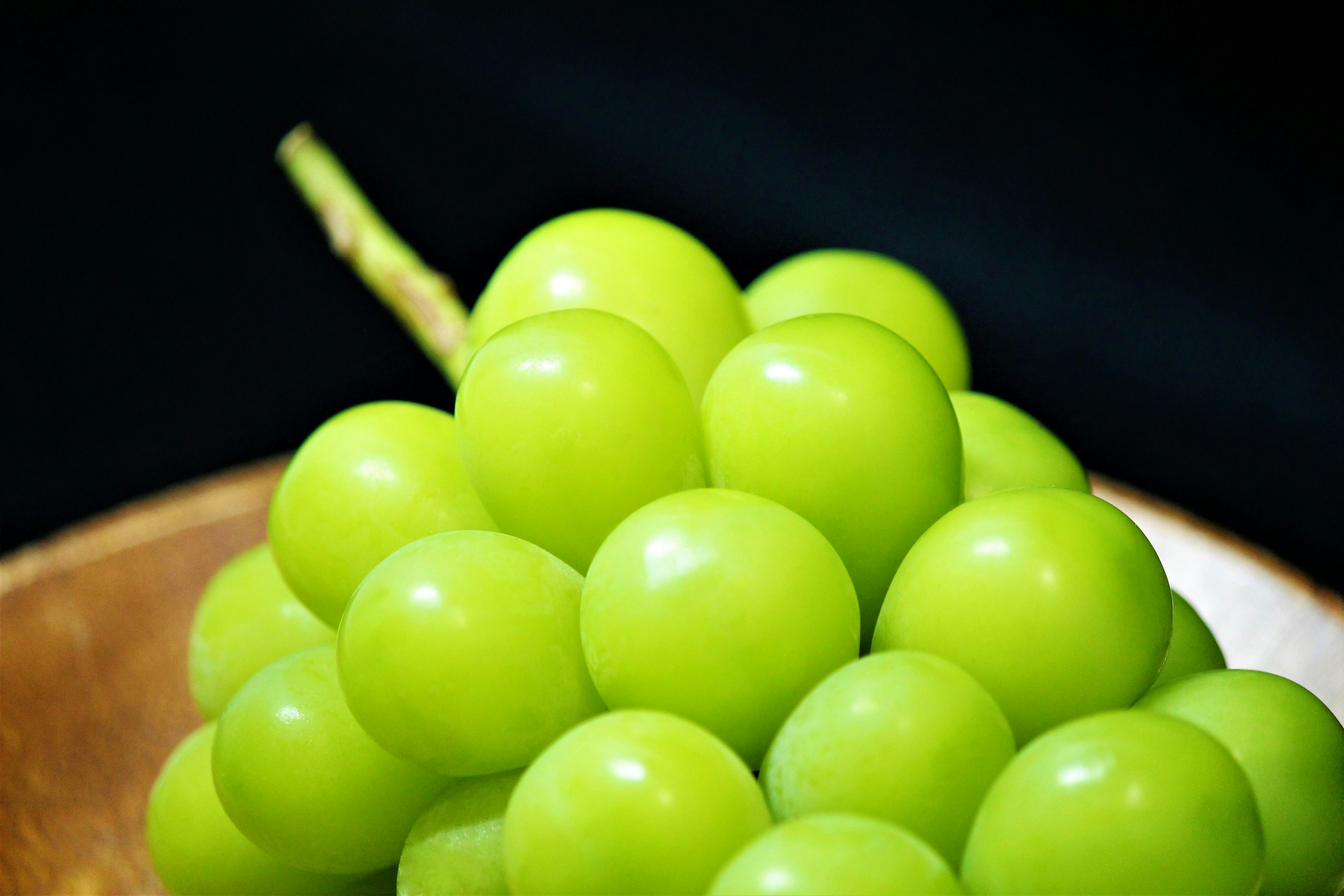 Un grappe de raisins verts dans un bol en bois