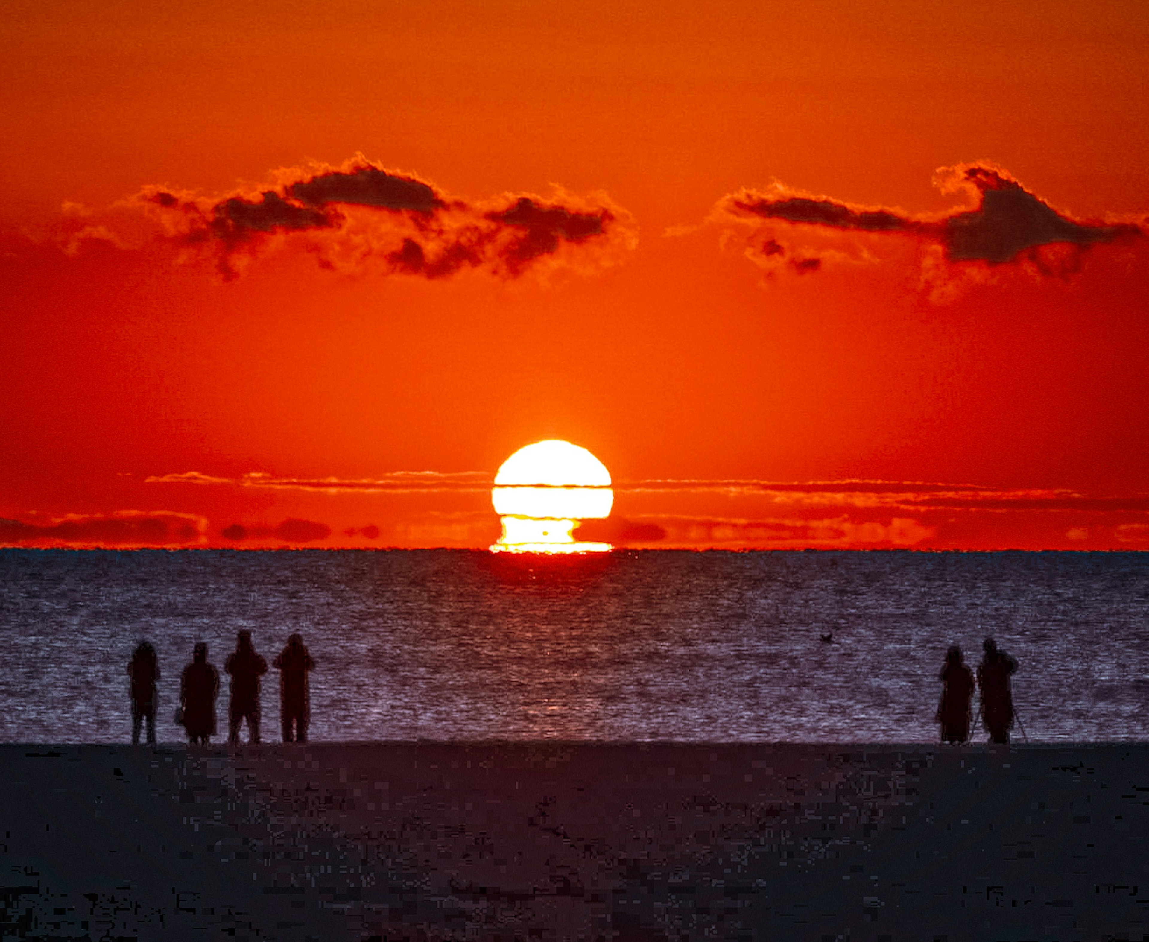 夕日が海に沈む美しい景色とシルエットの人々