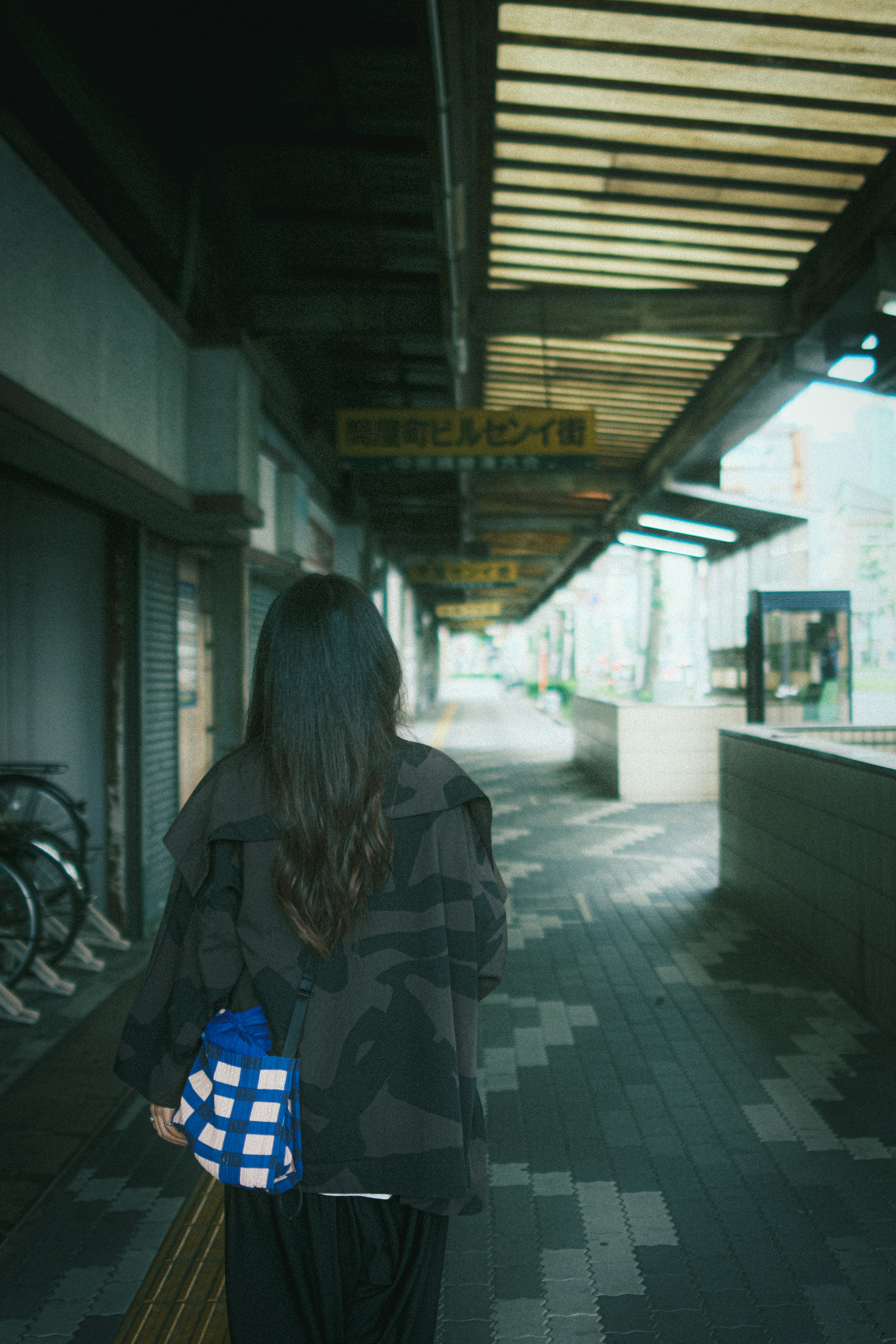 女性が後ろ向きに歩いている街の風景 彼女は青いバッグを持っている