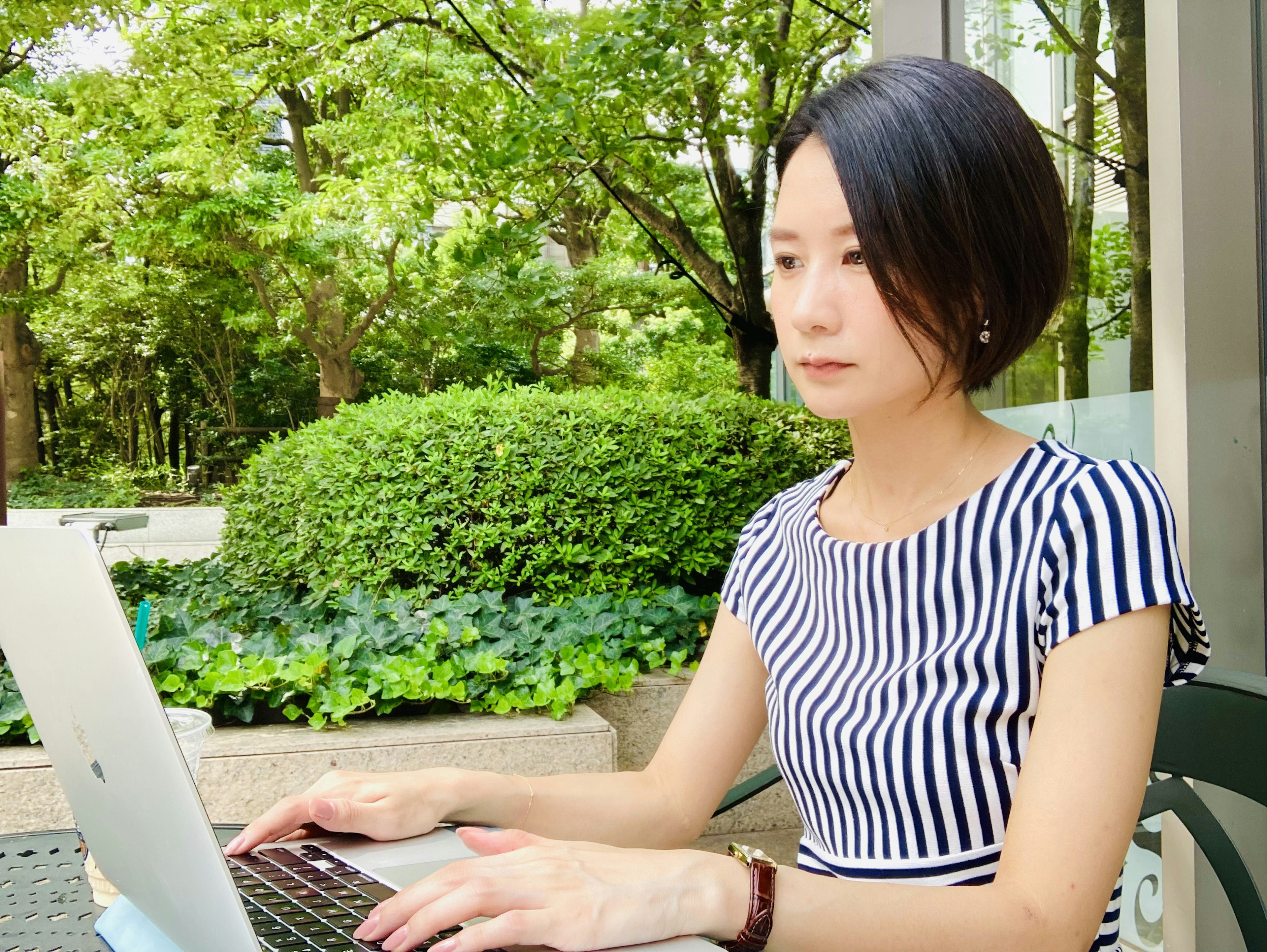 Mujer usando una computadora portátil en un entorno verde con un atuendo a rayas