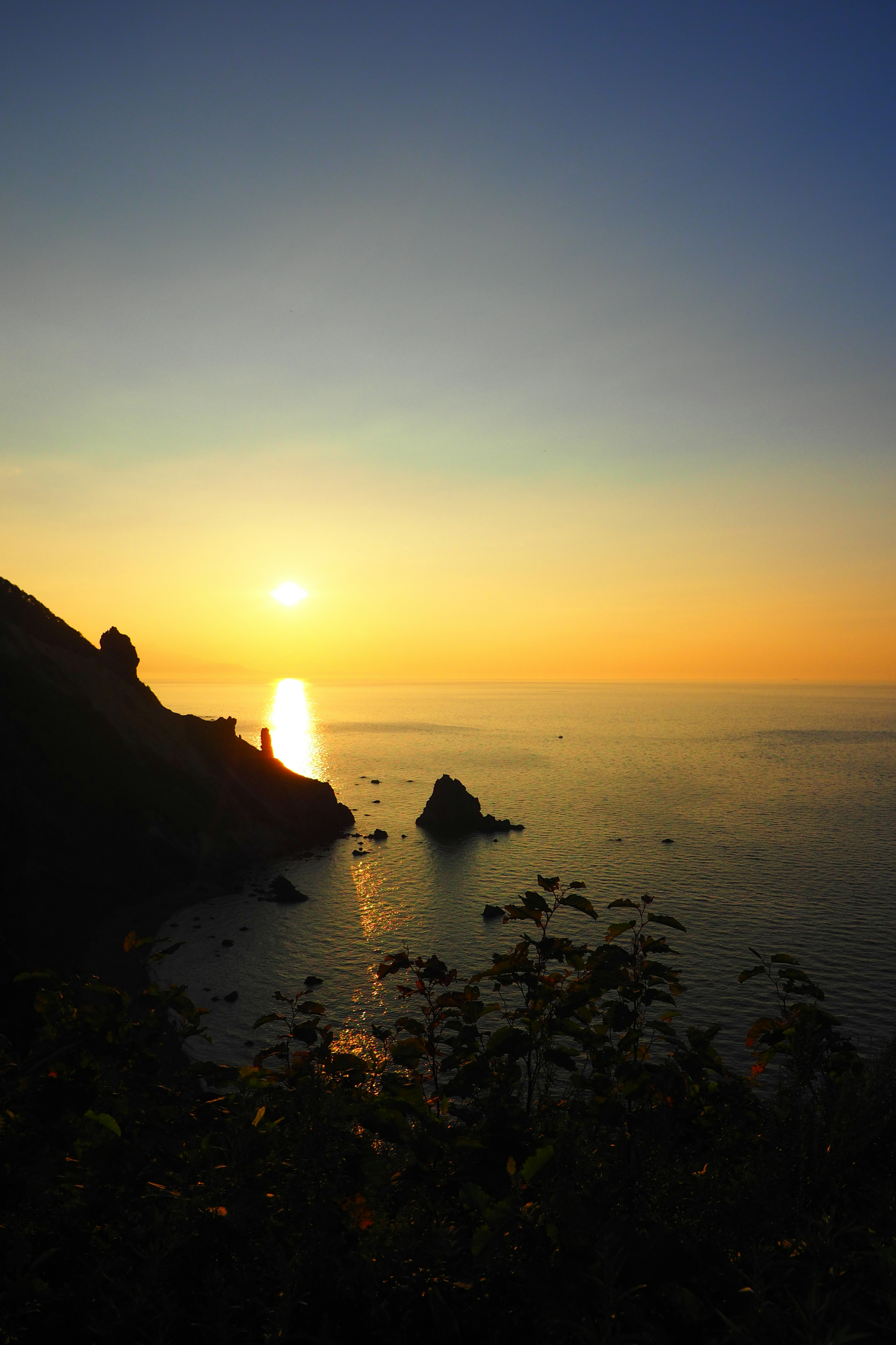 Wunderschöne Landschaft mit Sonnenuntergang über dem Ozean mit Bergen und Silhouetten