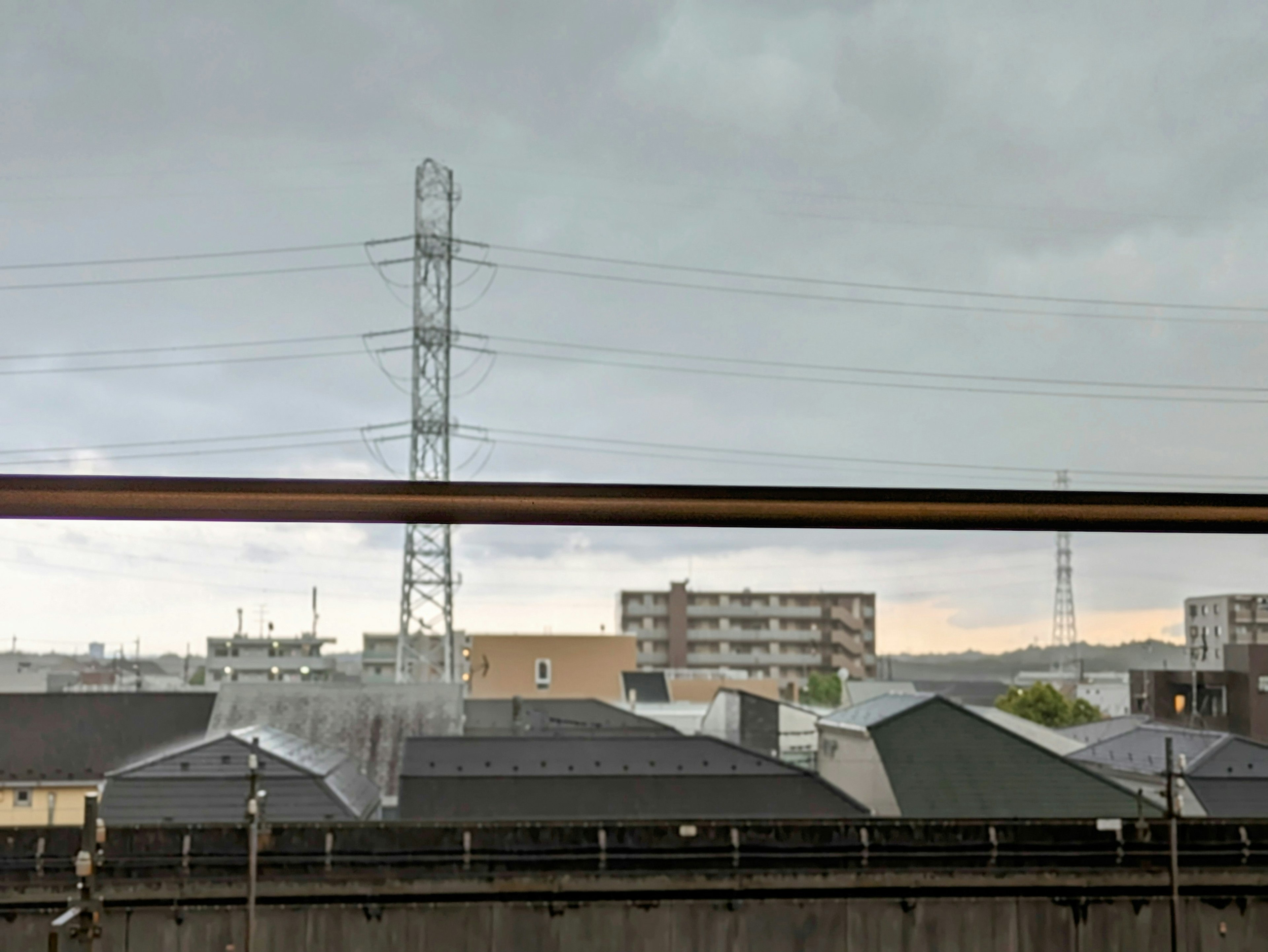 Stadtansicht unter bewölktem Himmel mit Stromleitungen und Wohngebäuden mit dunklen Dächern