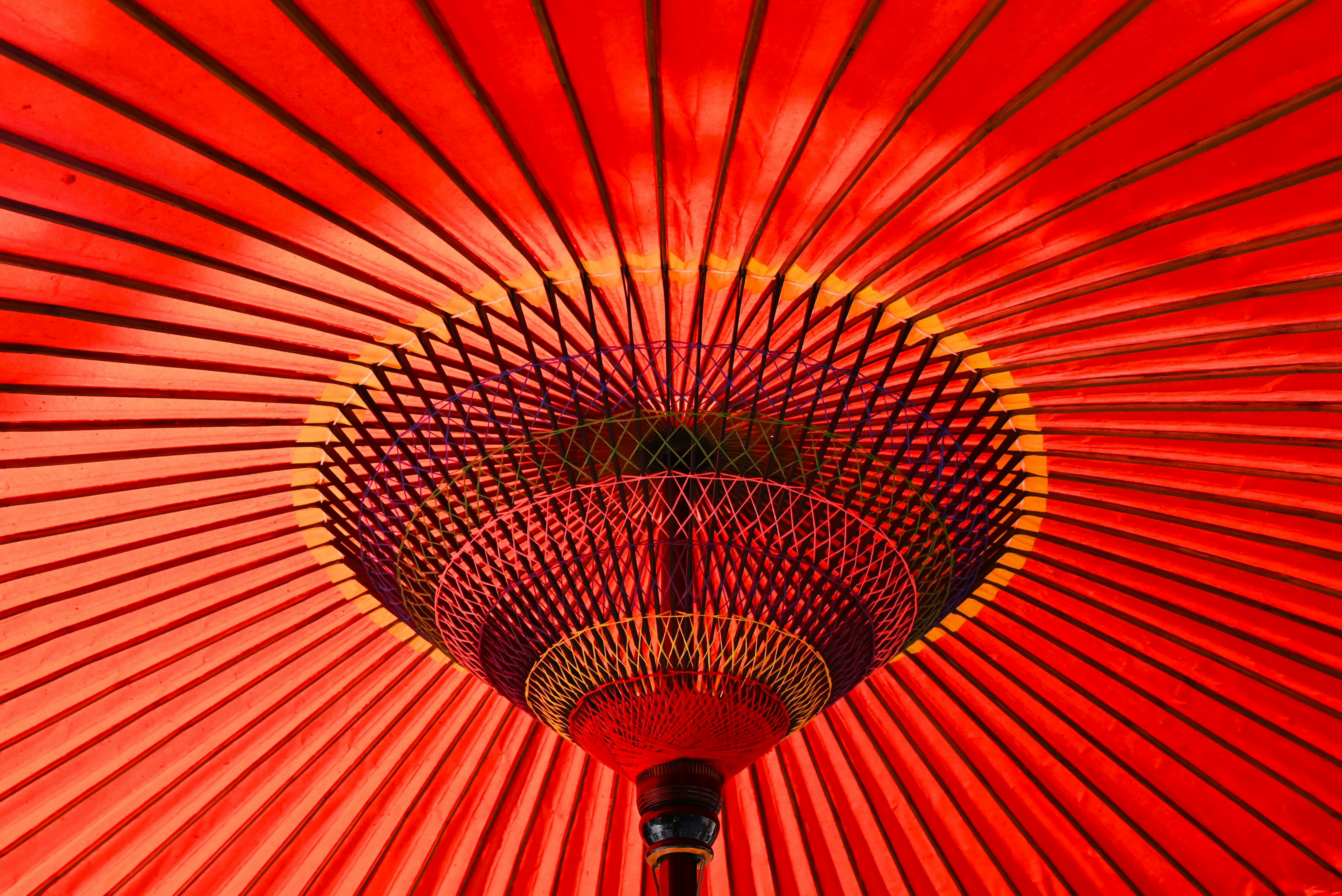 Interior view of a red Japanese umbrella showcasing radiating patterns and decorative elements