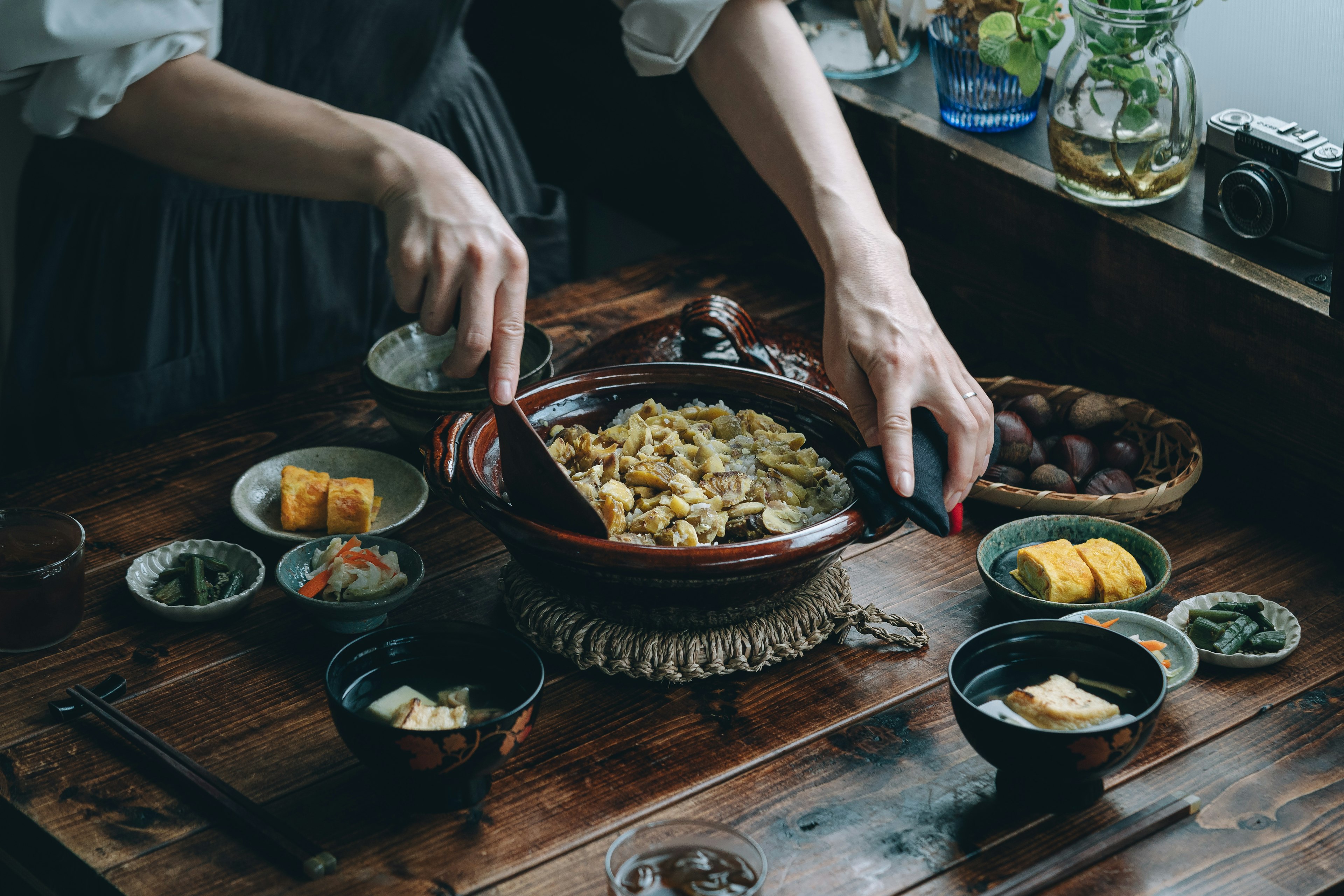 Une table garnie de plats japonais traditionnels et une main servant de la nourriture