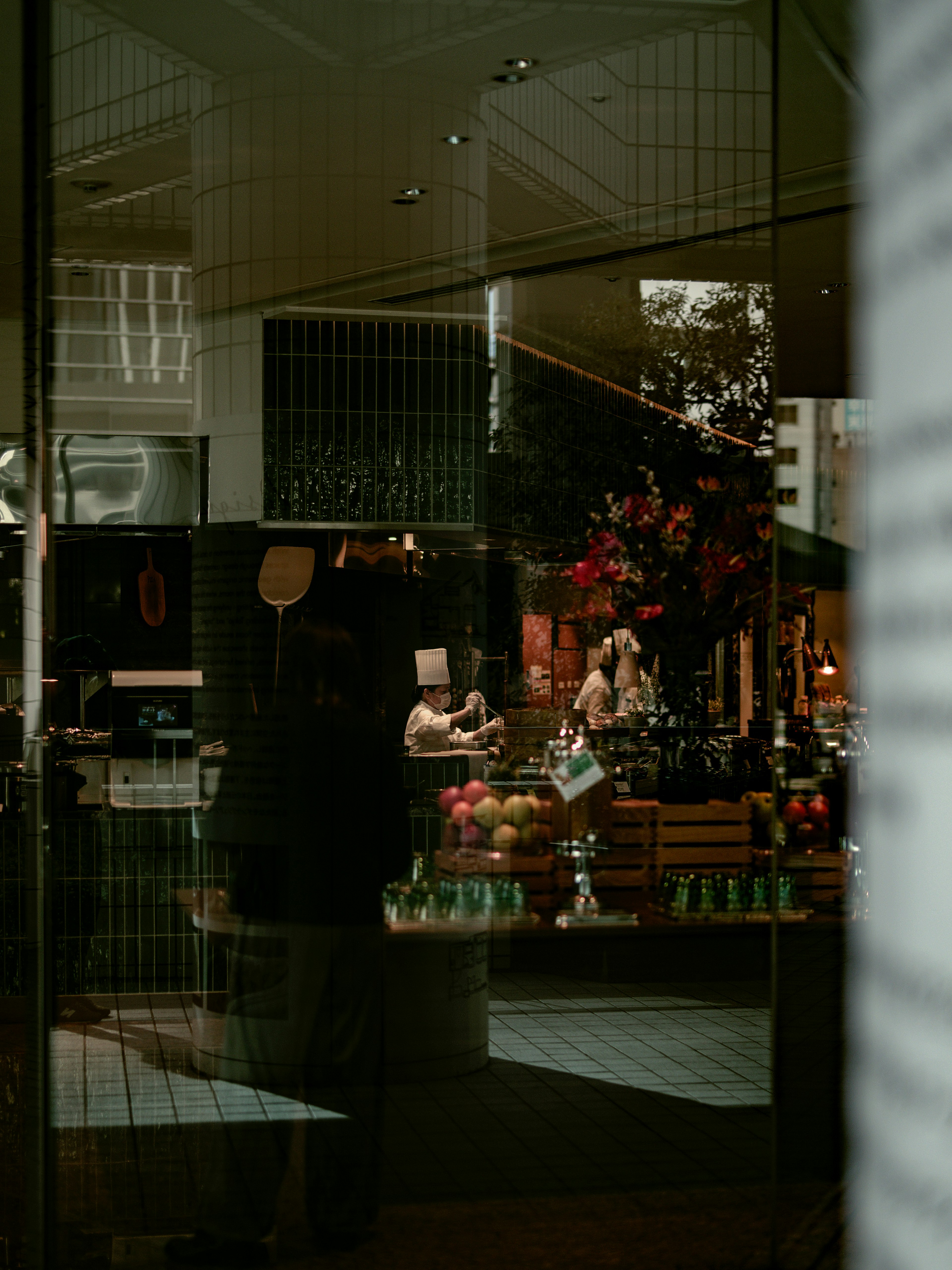 Reflexion eines Cafés und eines Blumengeschäfts mit Menschen im Glas