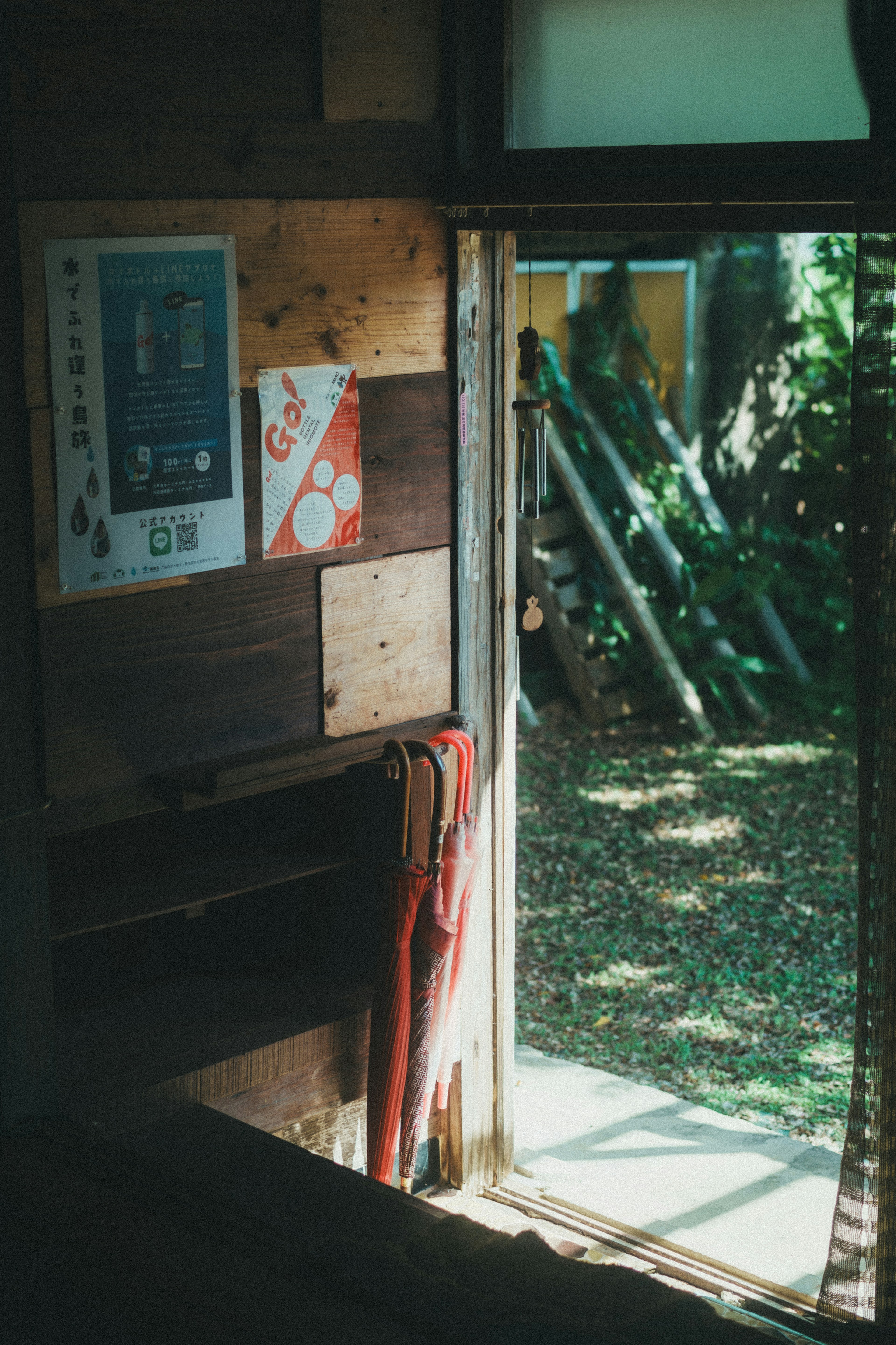 A wooden room with an open door revealing a garden outside